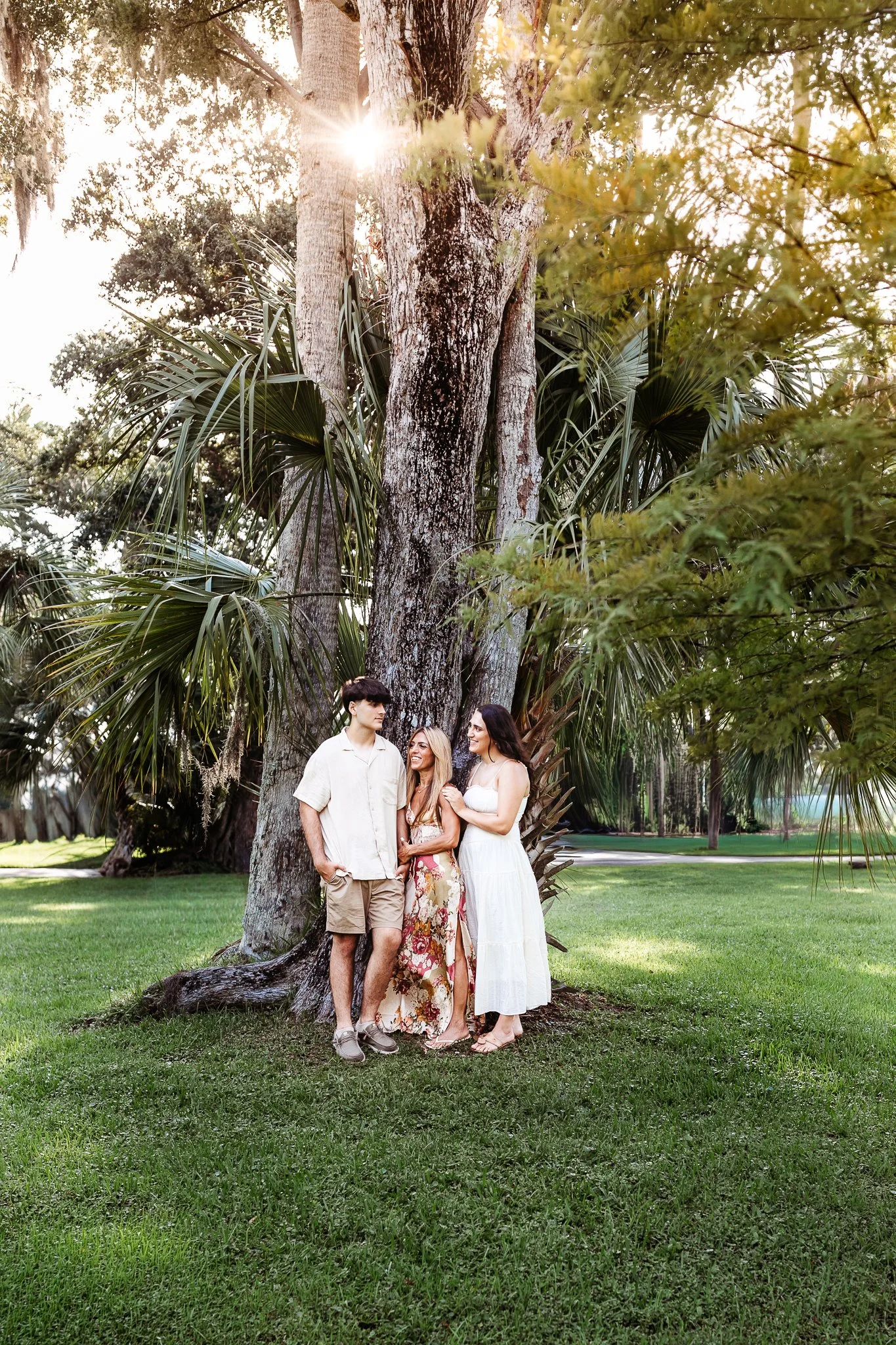 family under a palm tree at sunrise for a family photo before son leaves for college