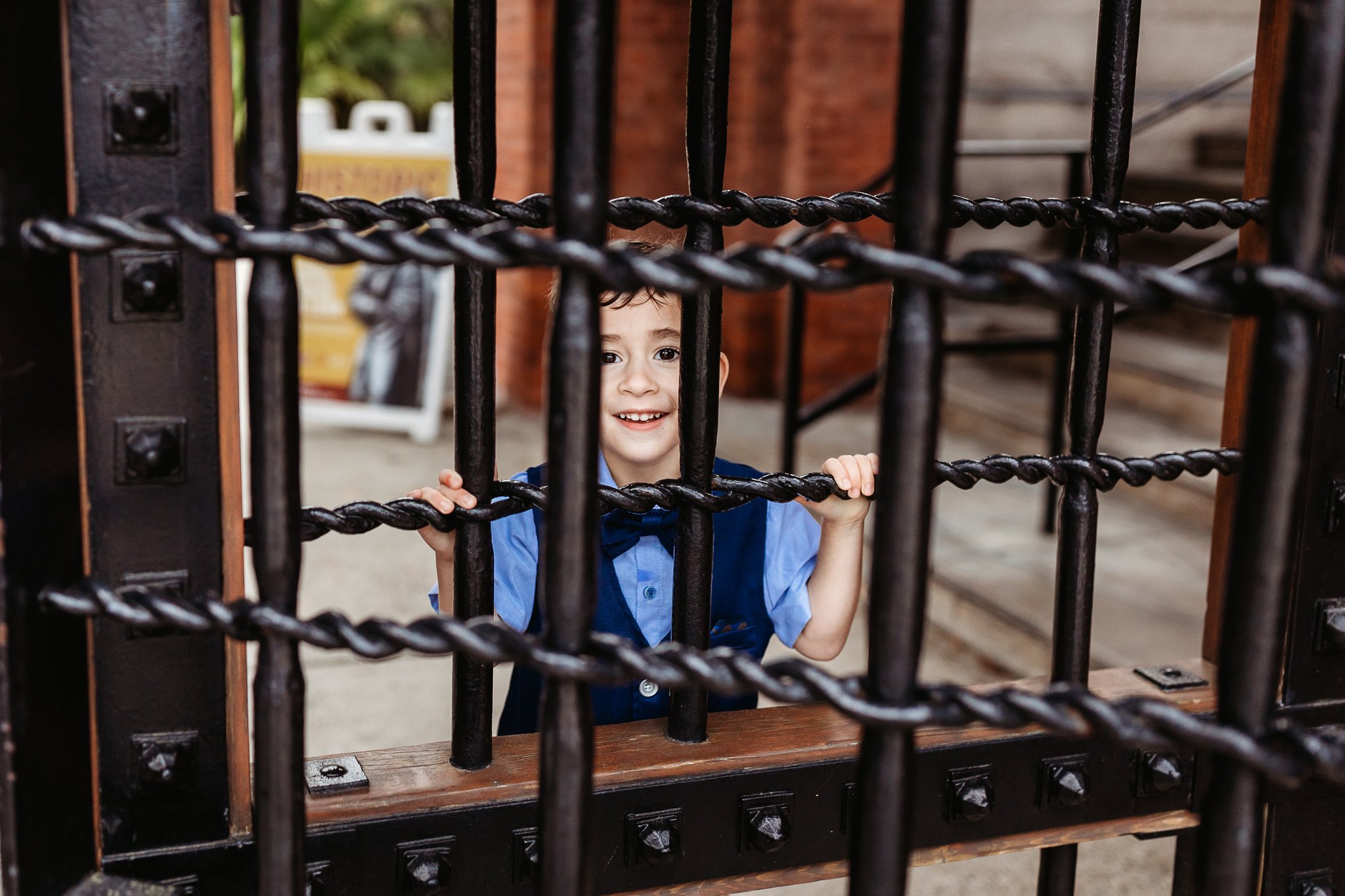 boy playing peak a boo behind a Gate at Flagler college