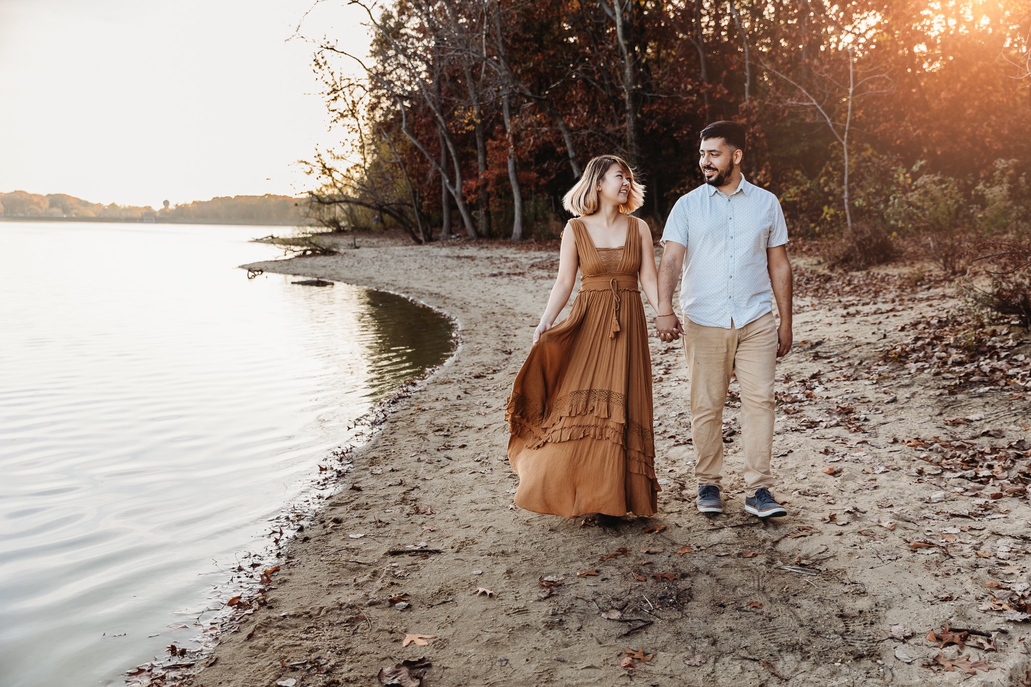 couple waking along the shore and they are laughing and looking at each other during photos