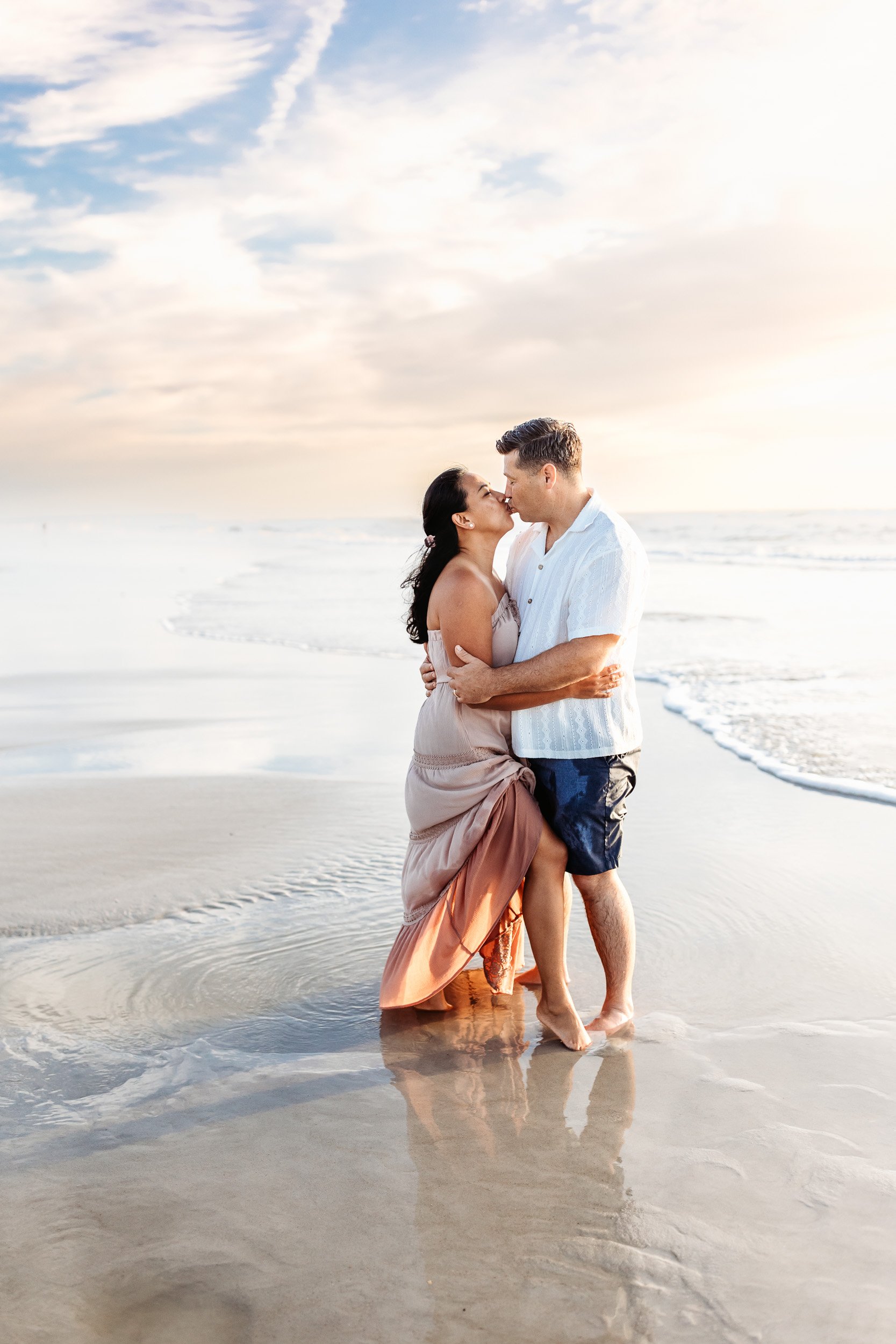 husband and wife kissing romantically on the beach at sunrise