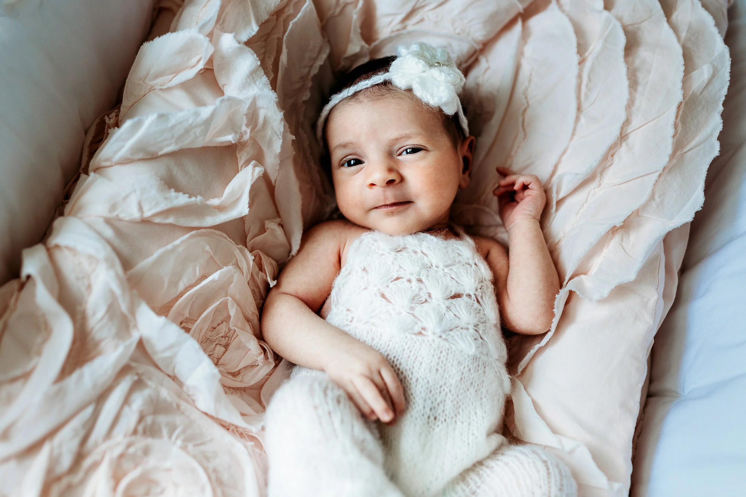 close up of a baby in a bassinet on a pink ruffled bedding in a Jacksonville in home newborn photo session