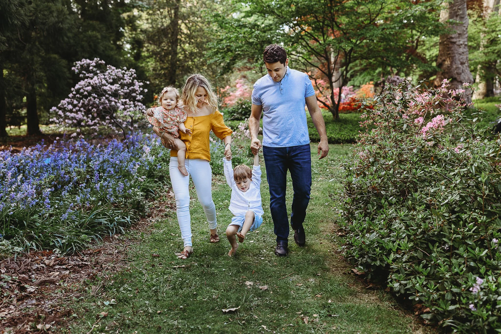 parents at a Washington oaks garden swinging a child as they walk