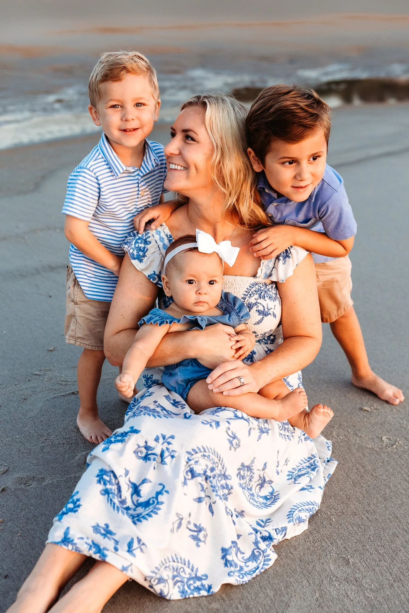 mother being embraced by her children on the beach at sunrise
