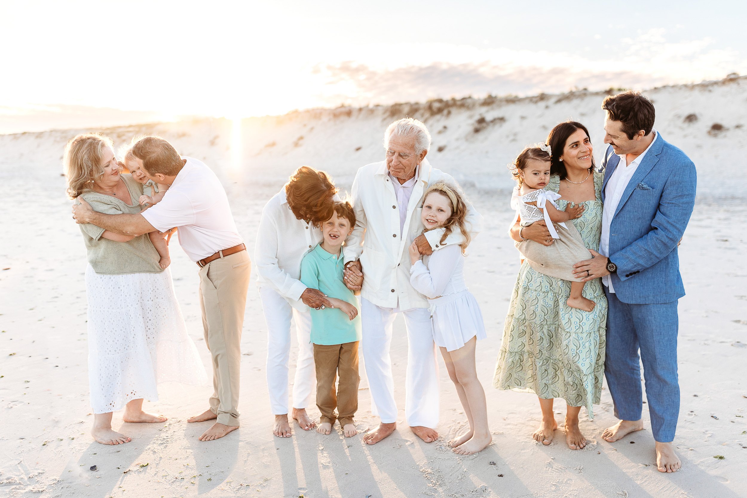 intimate moment of an extended family embraced in gorgeous sunset light in front of the iguana dune 