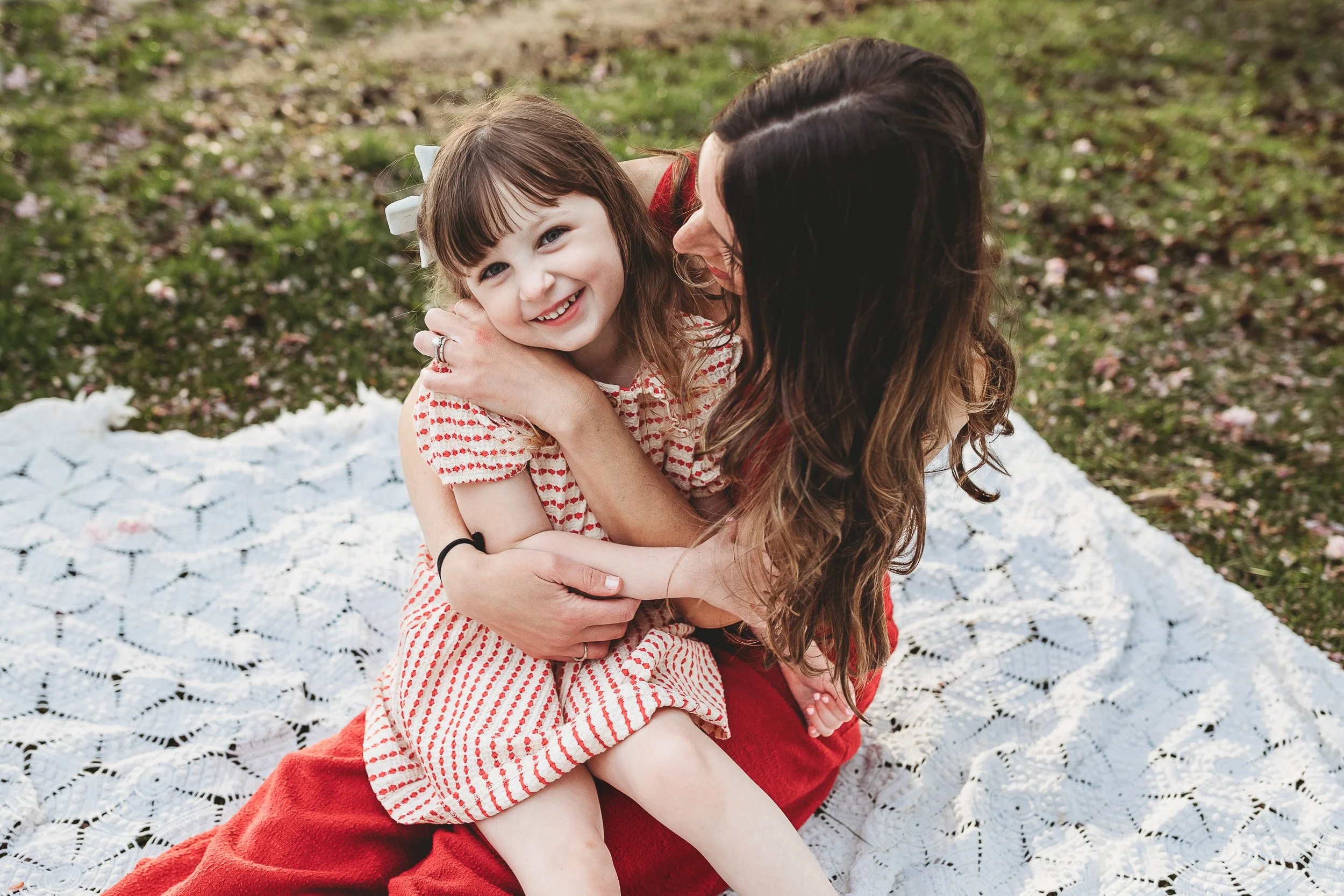 toddler girls state don mom's lap and mom is looking at the daughter and she is laughing