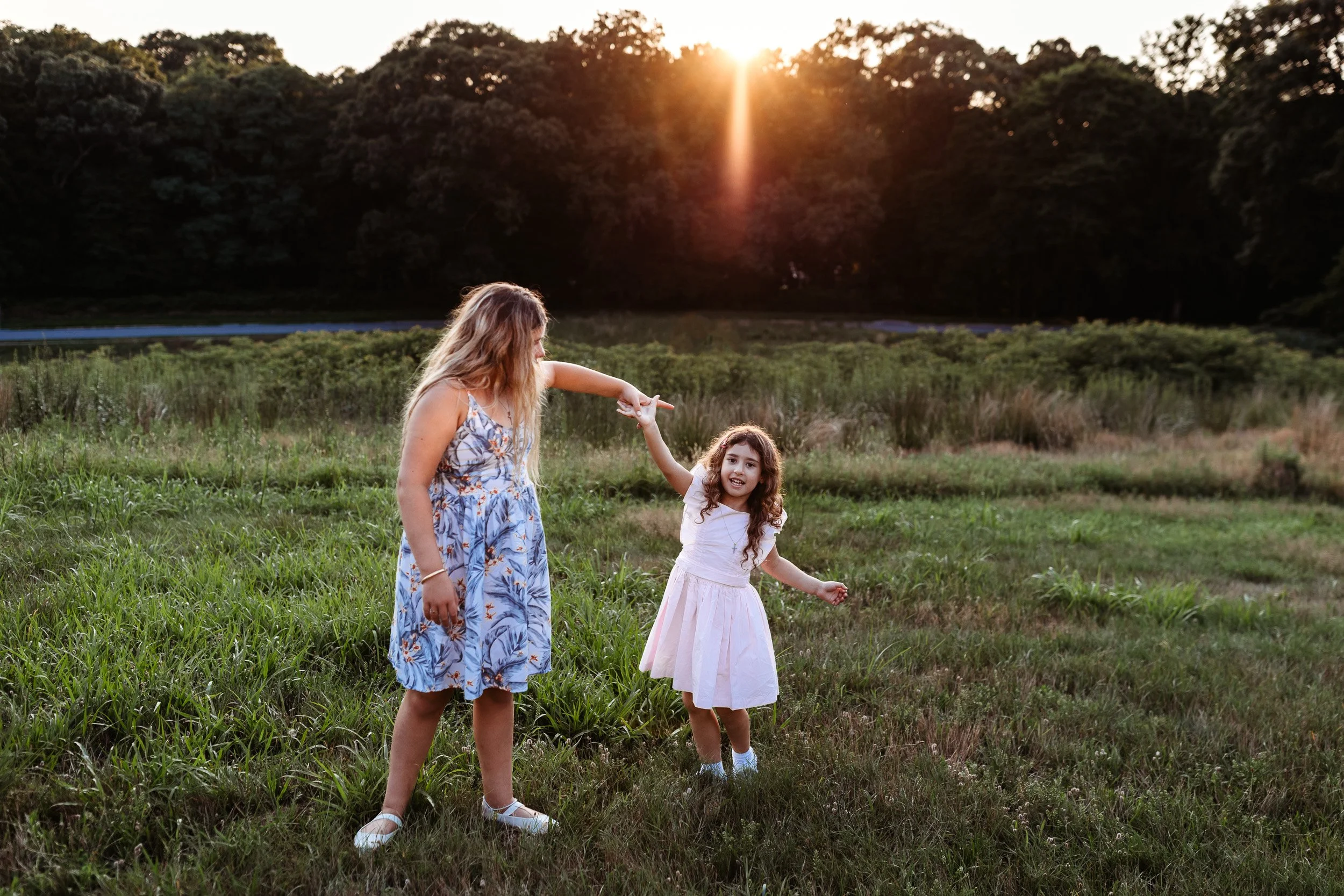 sisters dancing in the sunset during a family photo session
