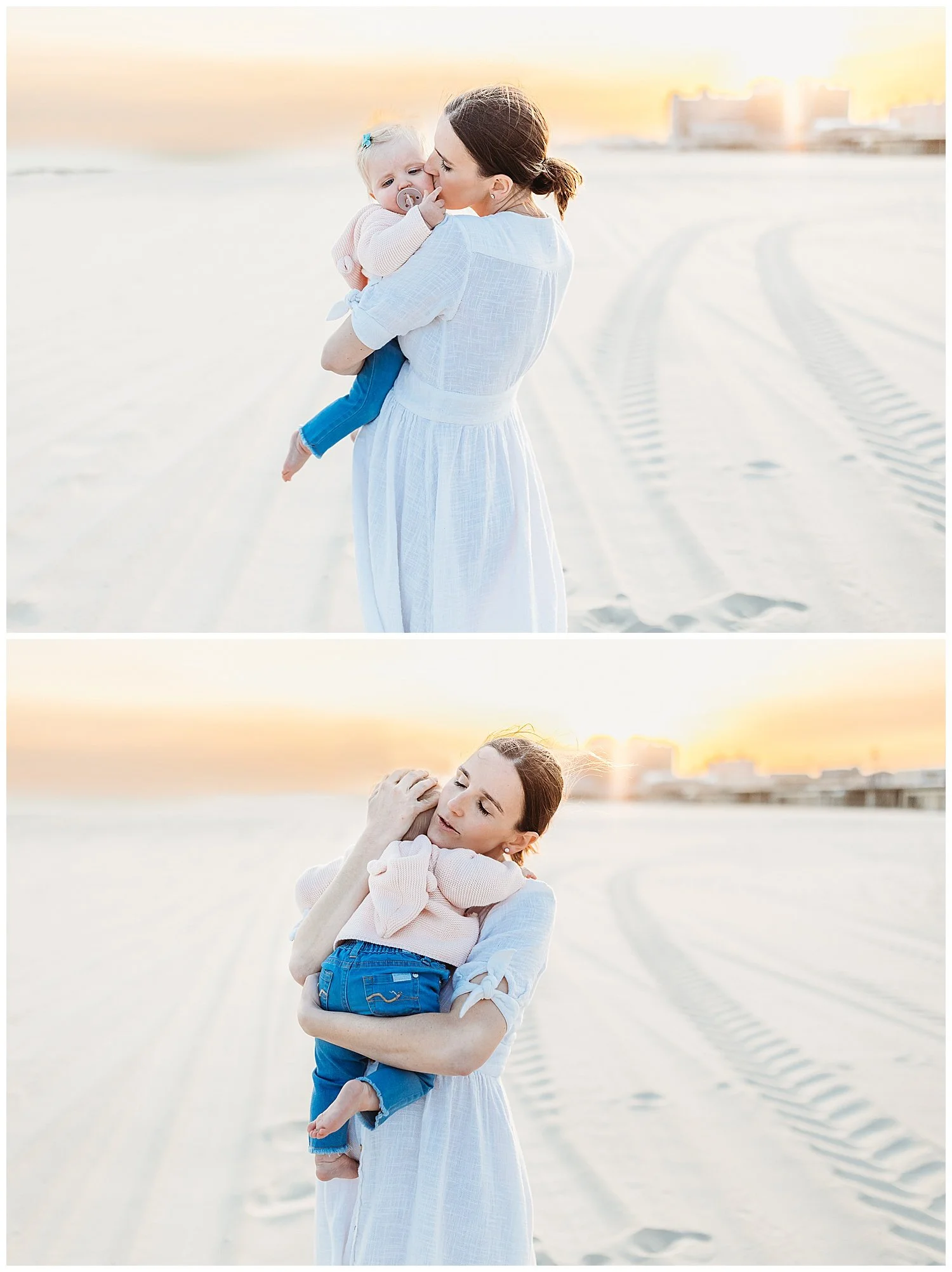 mother holding baby girl in white lace romper and kissing her.  the sky is golden pink and orange at sunset and they are on the beach.  the baby has a pacifier in her mouth and is sleepy