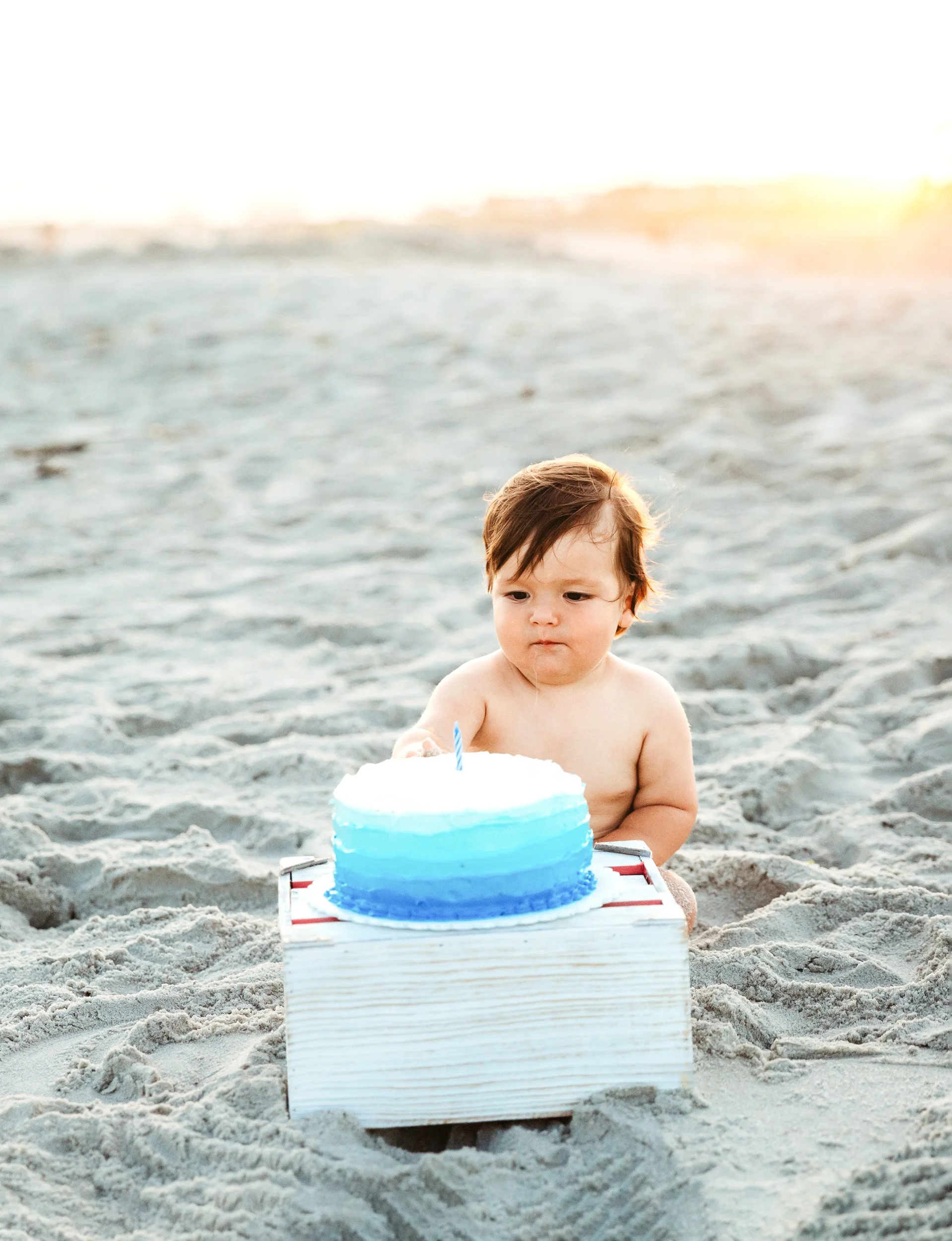 Baby next to smash cake during an outdoor beach cake smash session in St. Augustine