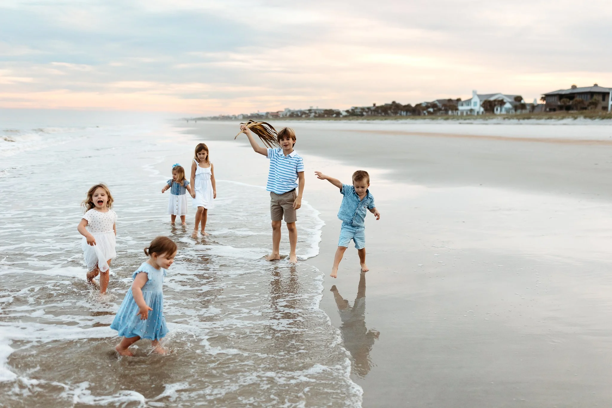 kids playing in the ocean at sunset