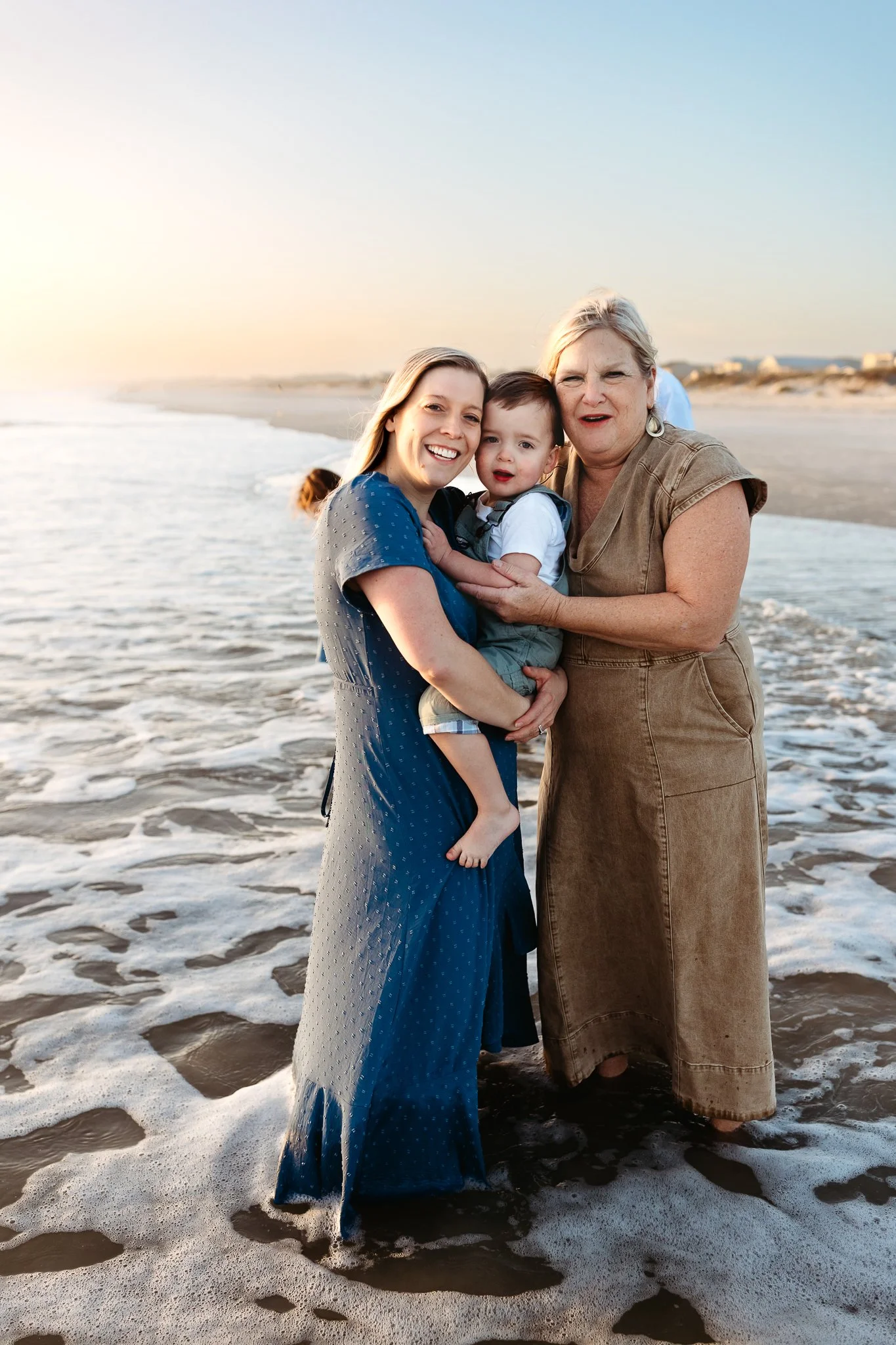 Grandmother, adult daughter, and young child smiling together during a Crescent Beach sunrise family session.