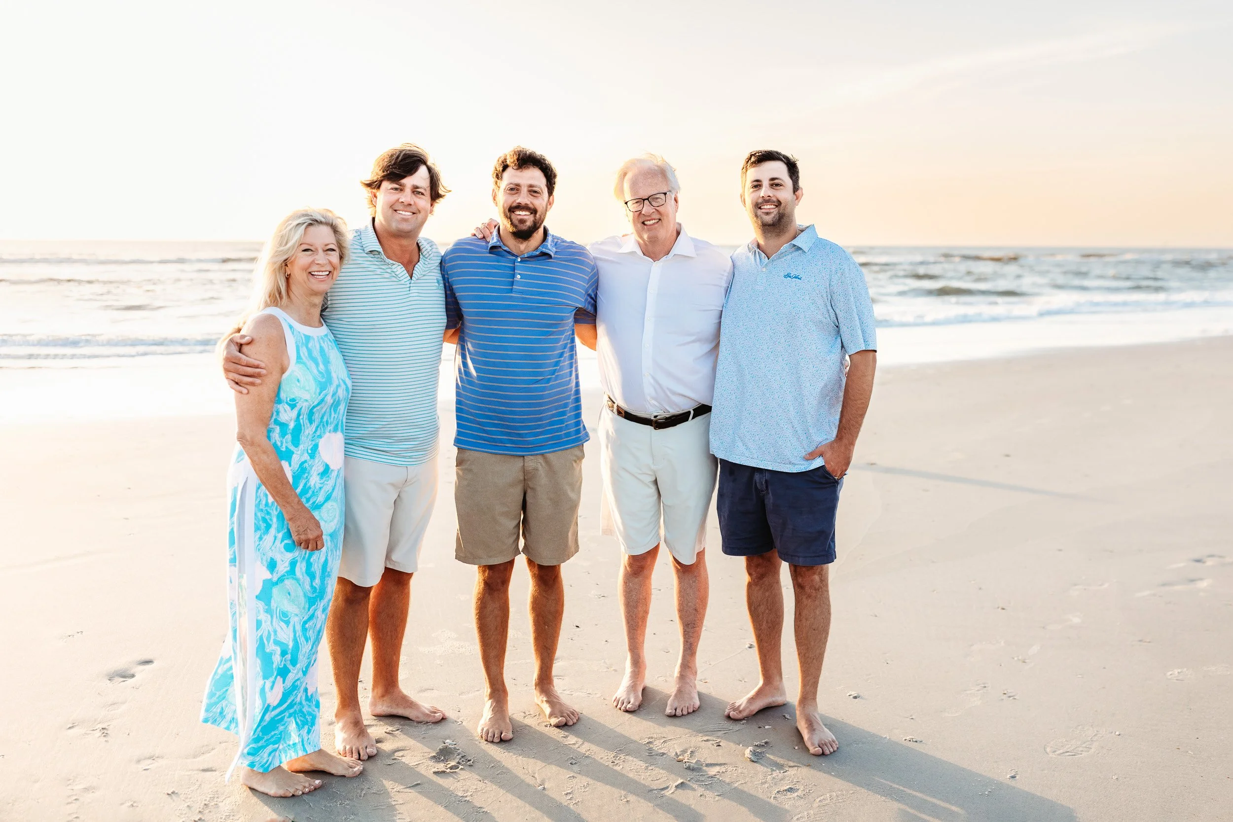 parents with adult children on the beach at sunrise with gorgeous orange glow over the ocean