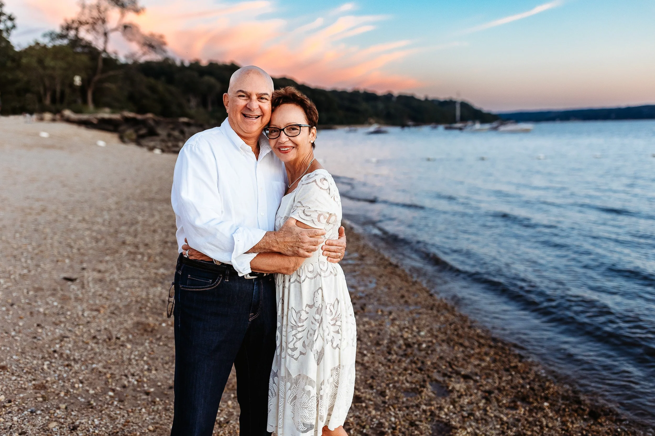 grandma and grandpa embraced with a stunning pink and blue sunset sky behind them in a marina in st augustine 