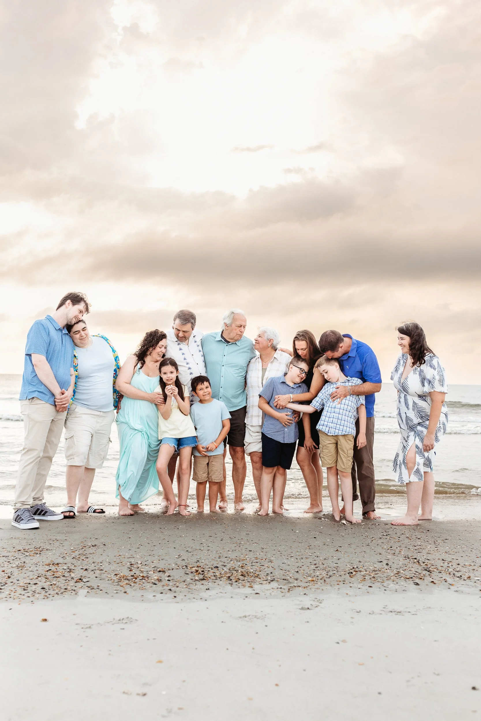 family embraced on the beach at sunrise and not looking at the camera and beaitfil sunrise over cloudy sky and ocean