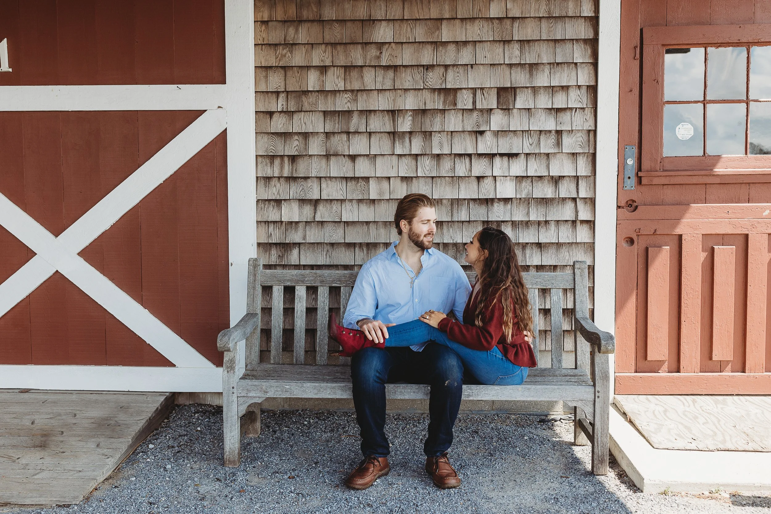 couple seated outdoors on a bench laughing while on a date in San Pablo