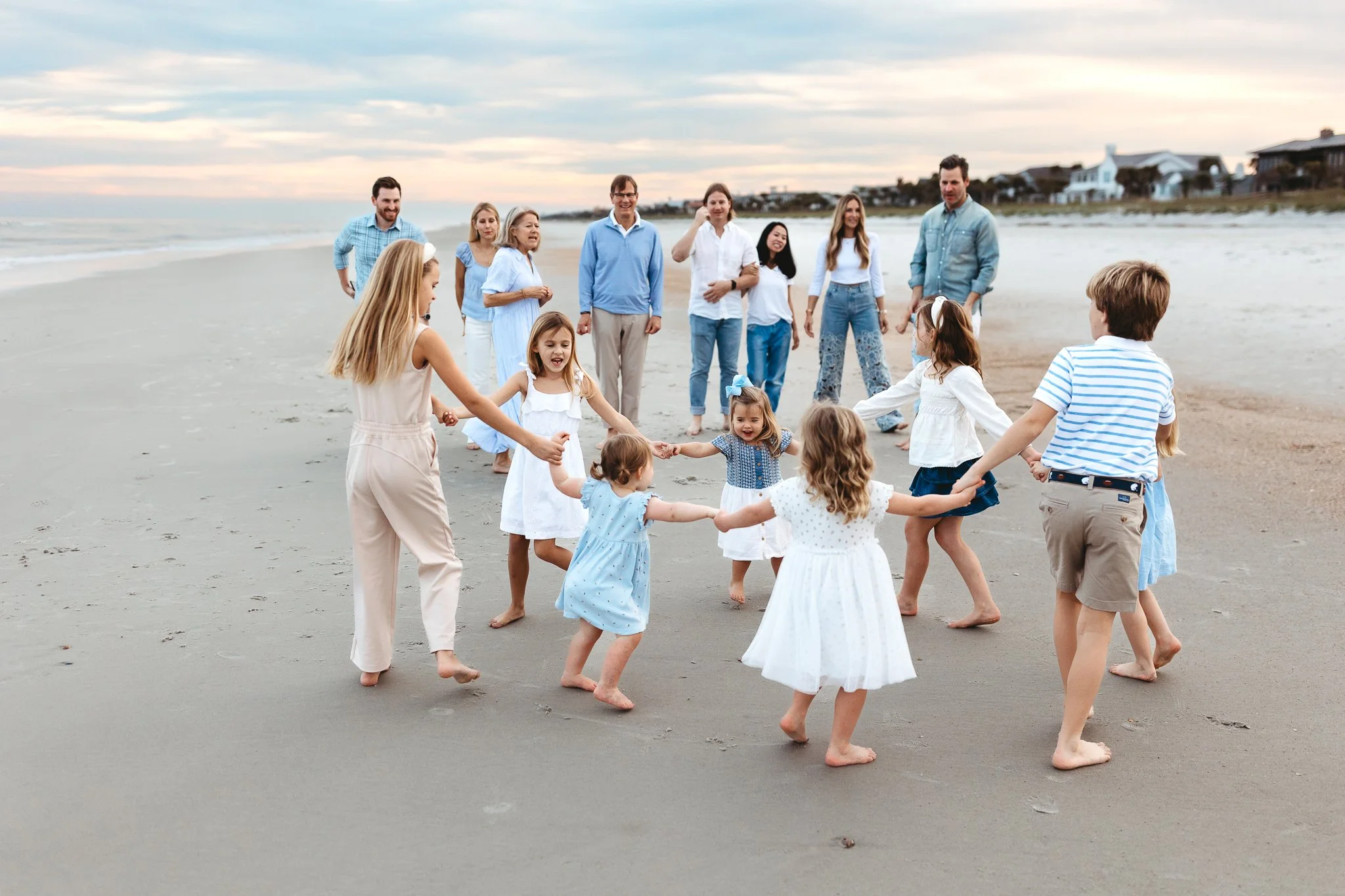 kids playing in the sand while family watches and it is sunset