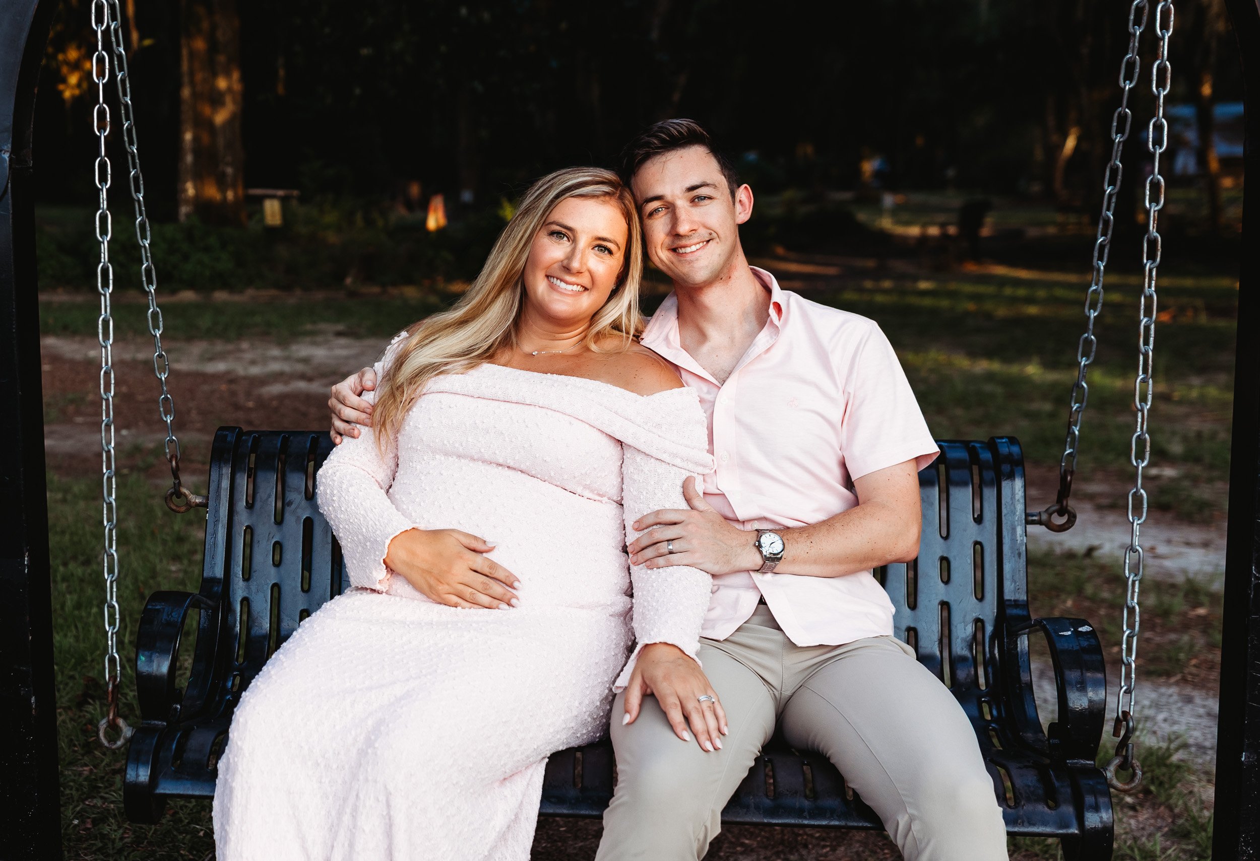 couple seated on a metal swing in alpine groves park on the st john's river for a portrait while they hold each other