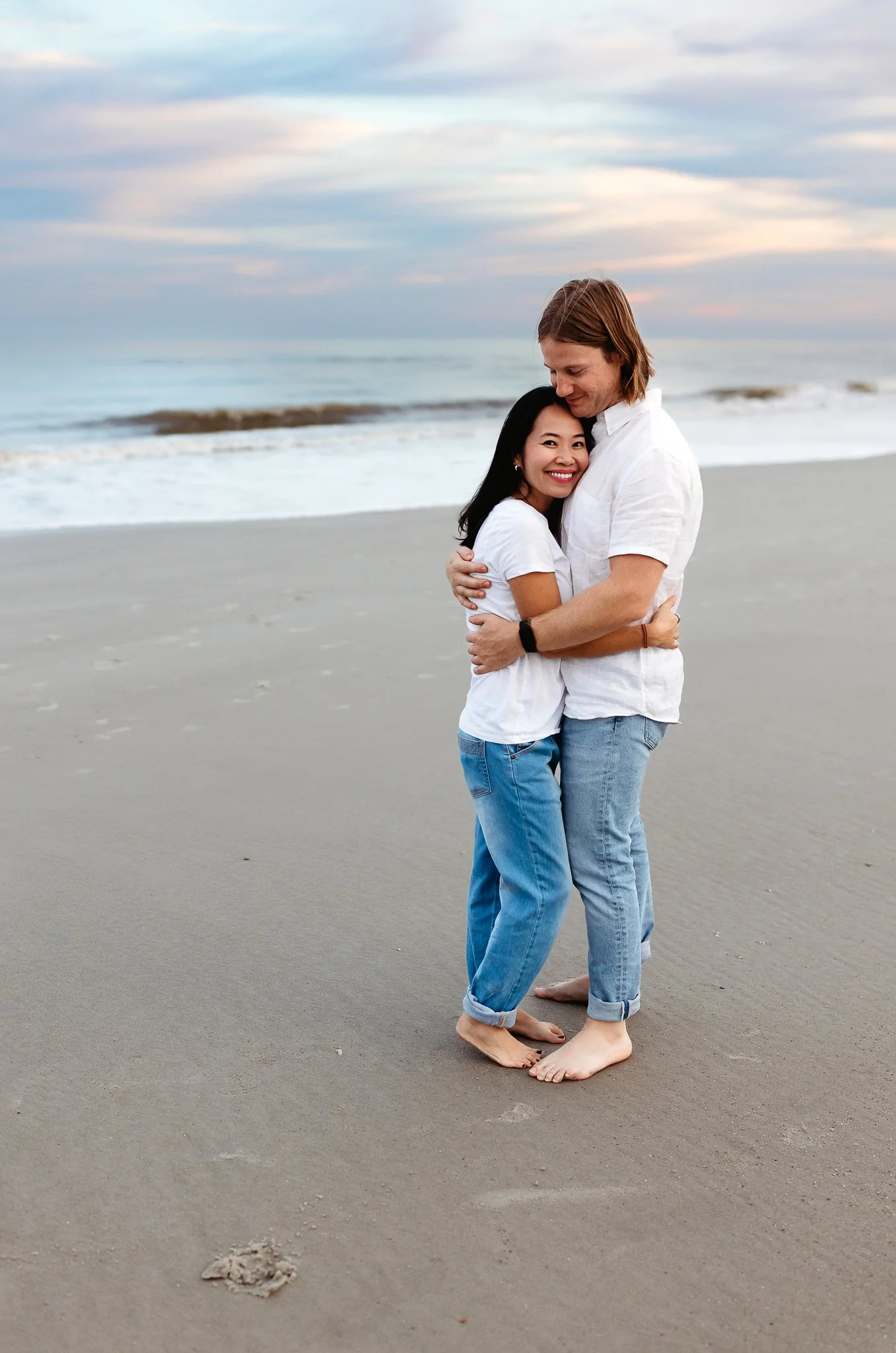 man kissing wife on the head at sunset on the beach