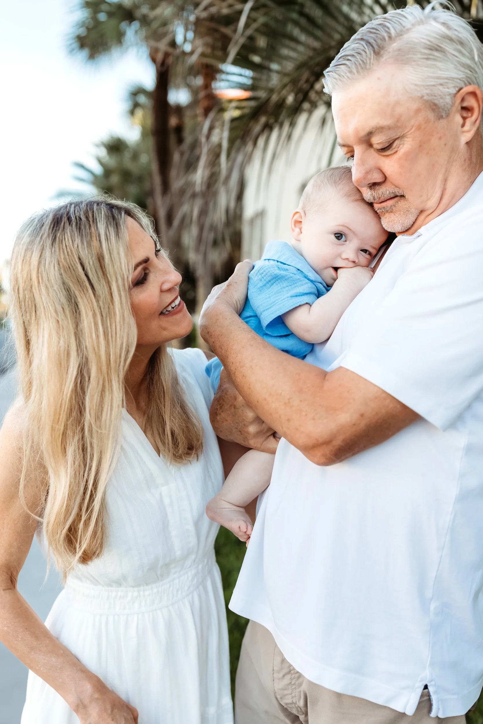 grandpa snuggling grandchild at the end of a beach vacation photo session