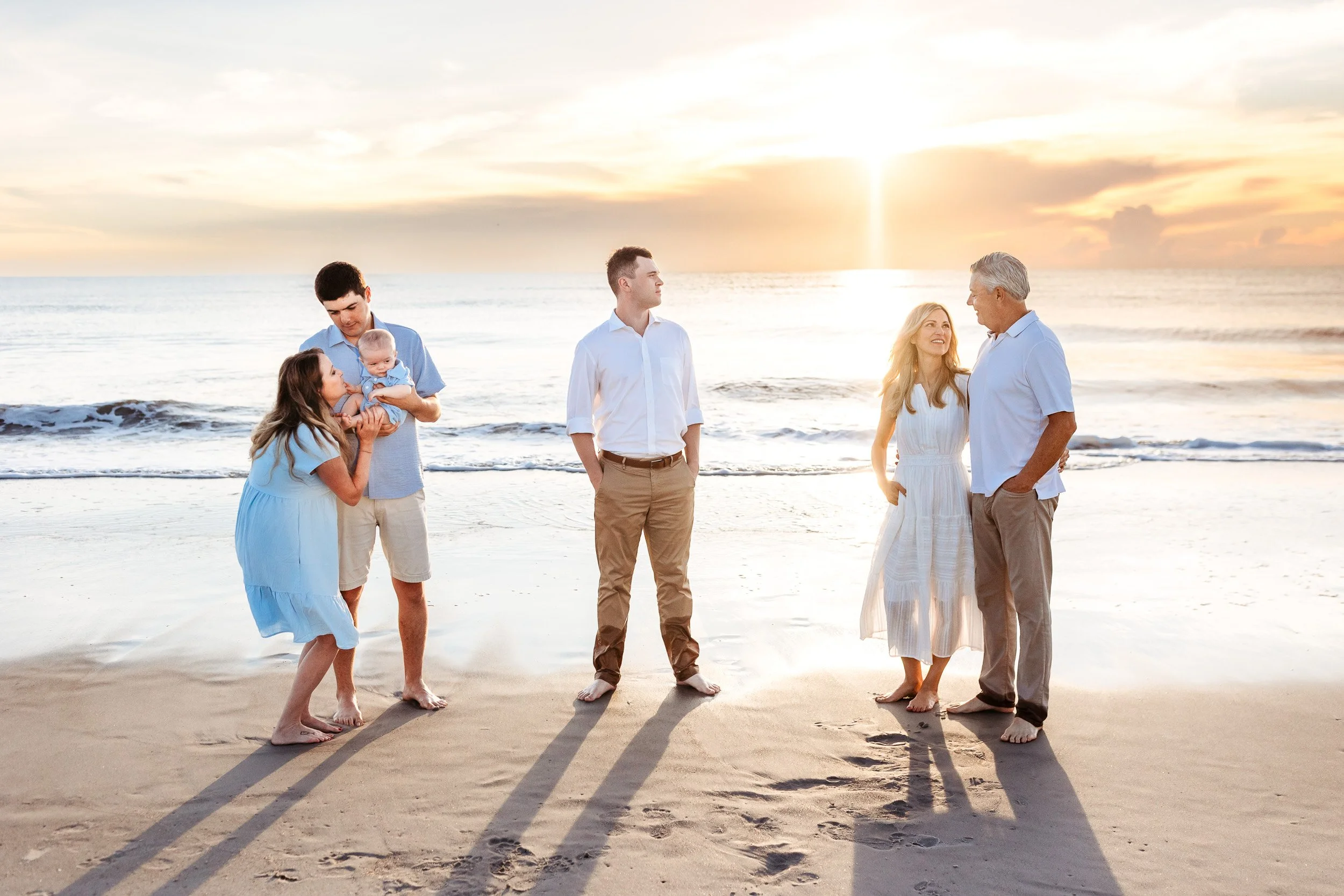 family along the ocean at sunrise and they are alll interaction in some way