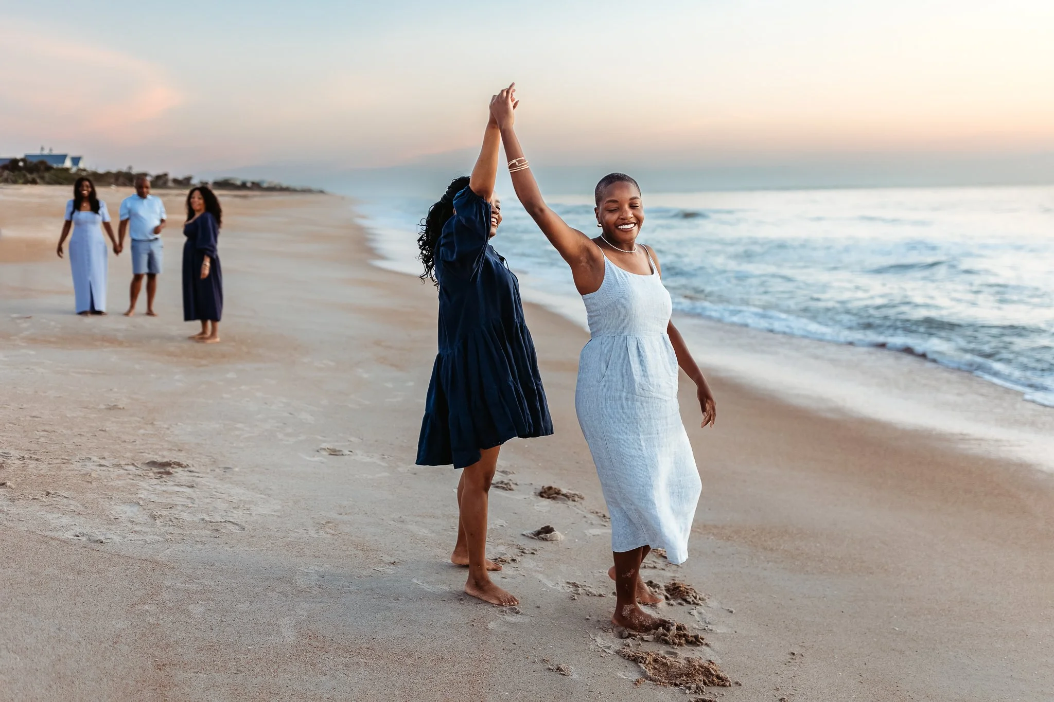 adult sisters dancing on the beach at their vacation rental in Ponte Vedra Beach for family photos on the beach at sunrise