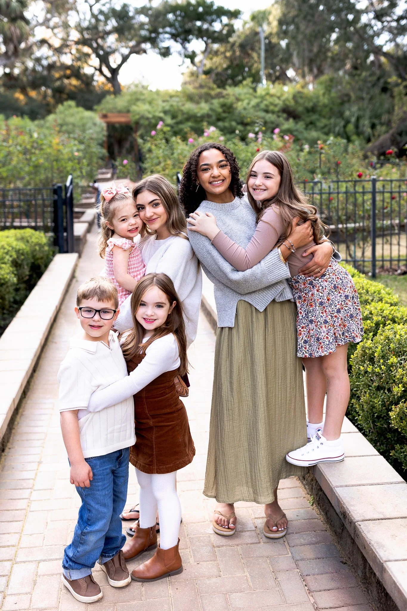 Children in the rose garden at Washington oaks gardens for spring family photos and they are hugging