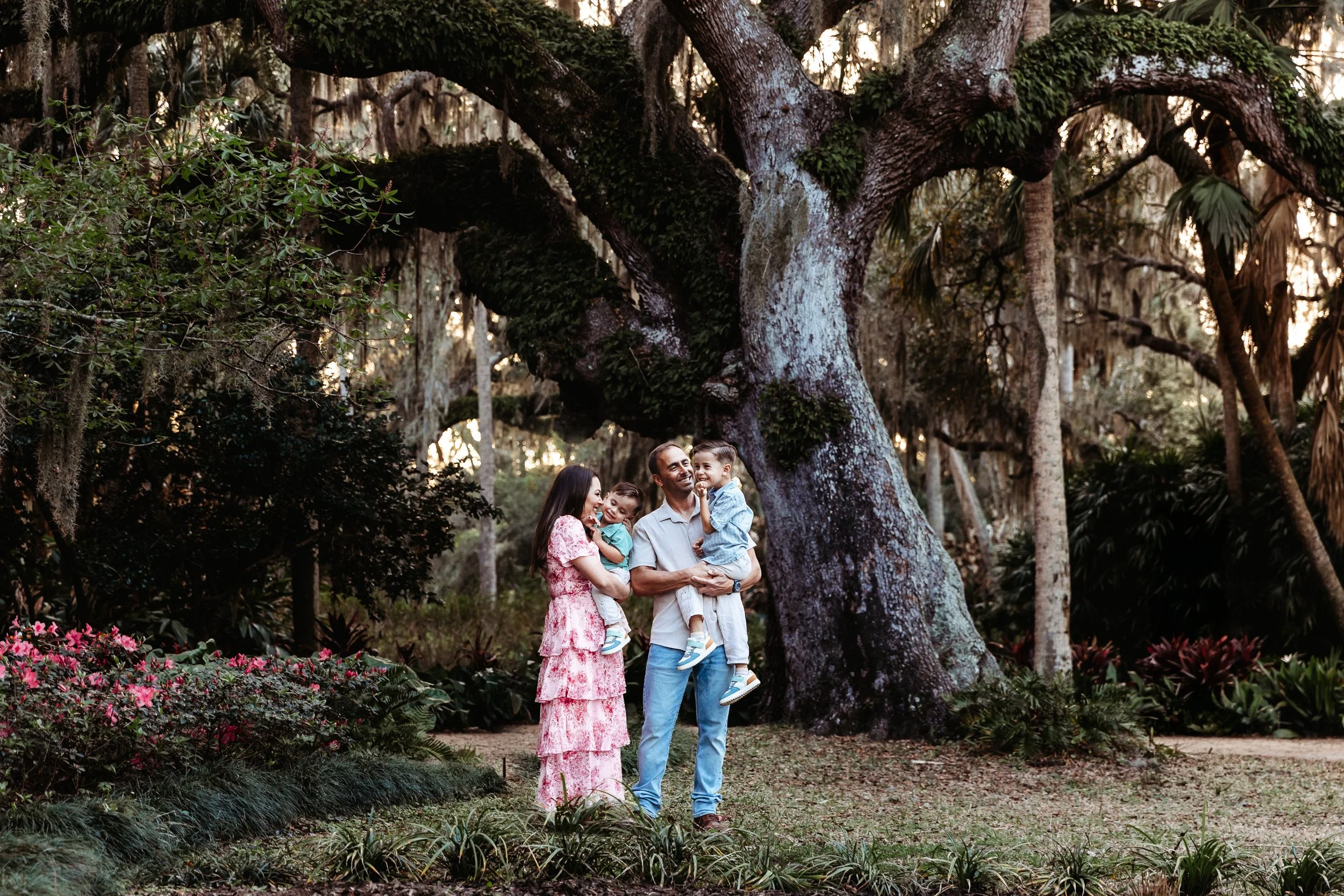 family standing under a large oak tree embraced during family photos