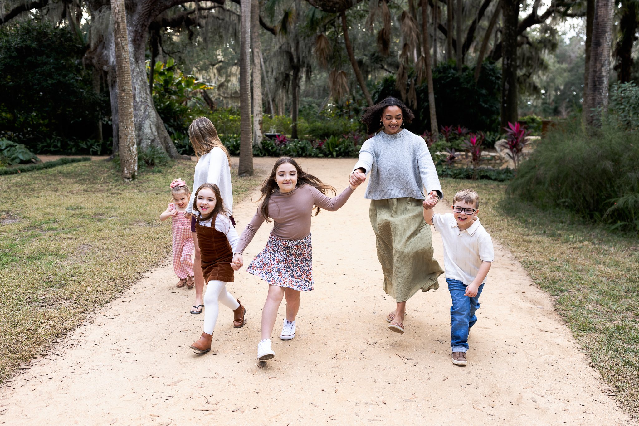 cousins running hand in hand in a garden laughing