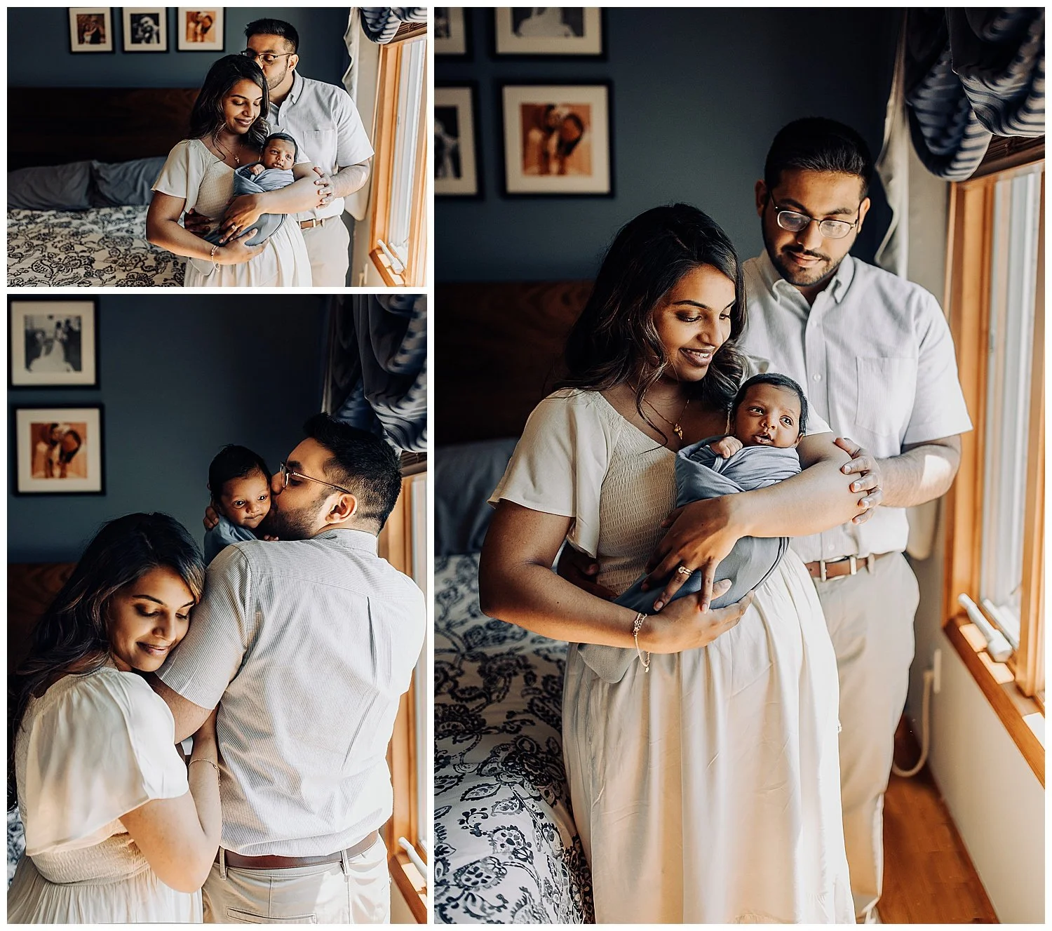 parents standing in front of a window holding a swaddled baby and the baby is looking out the window while the dad kisses the mom