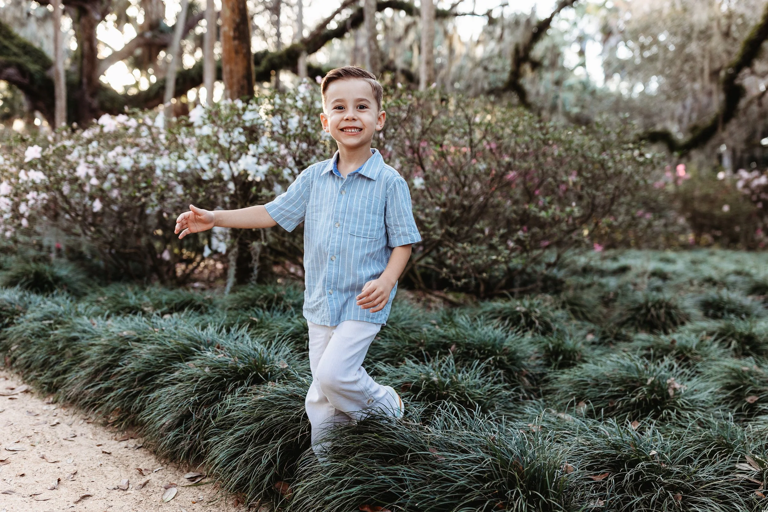 boy running through grass during family photos and he is laughing