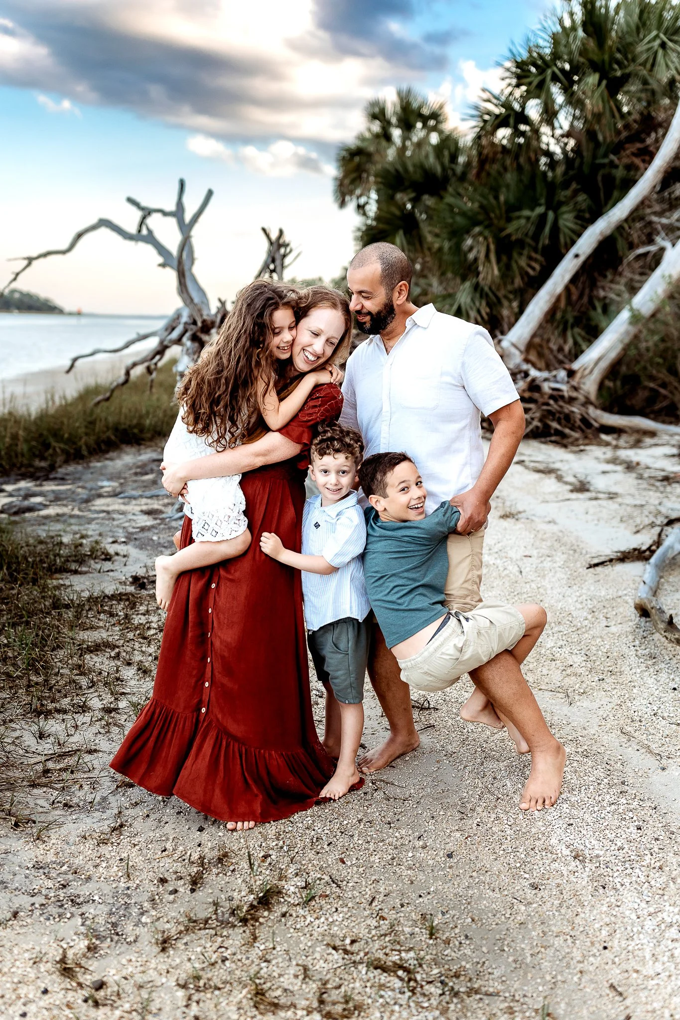 family on a driftwood beach at sunset