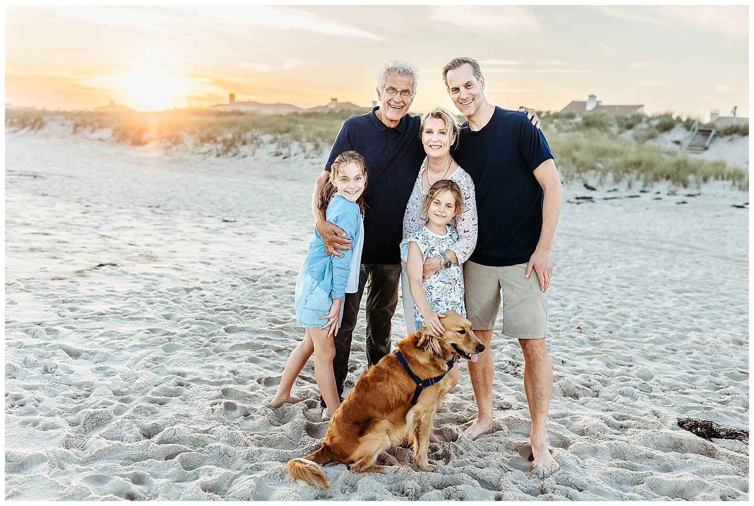 family portrait with son grandparents, granddaughters and golden retriever on the beach at sunset