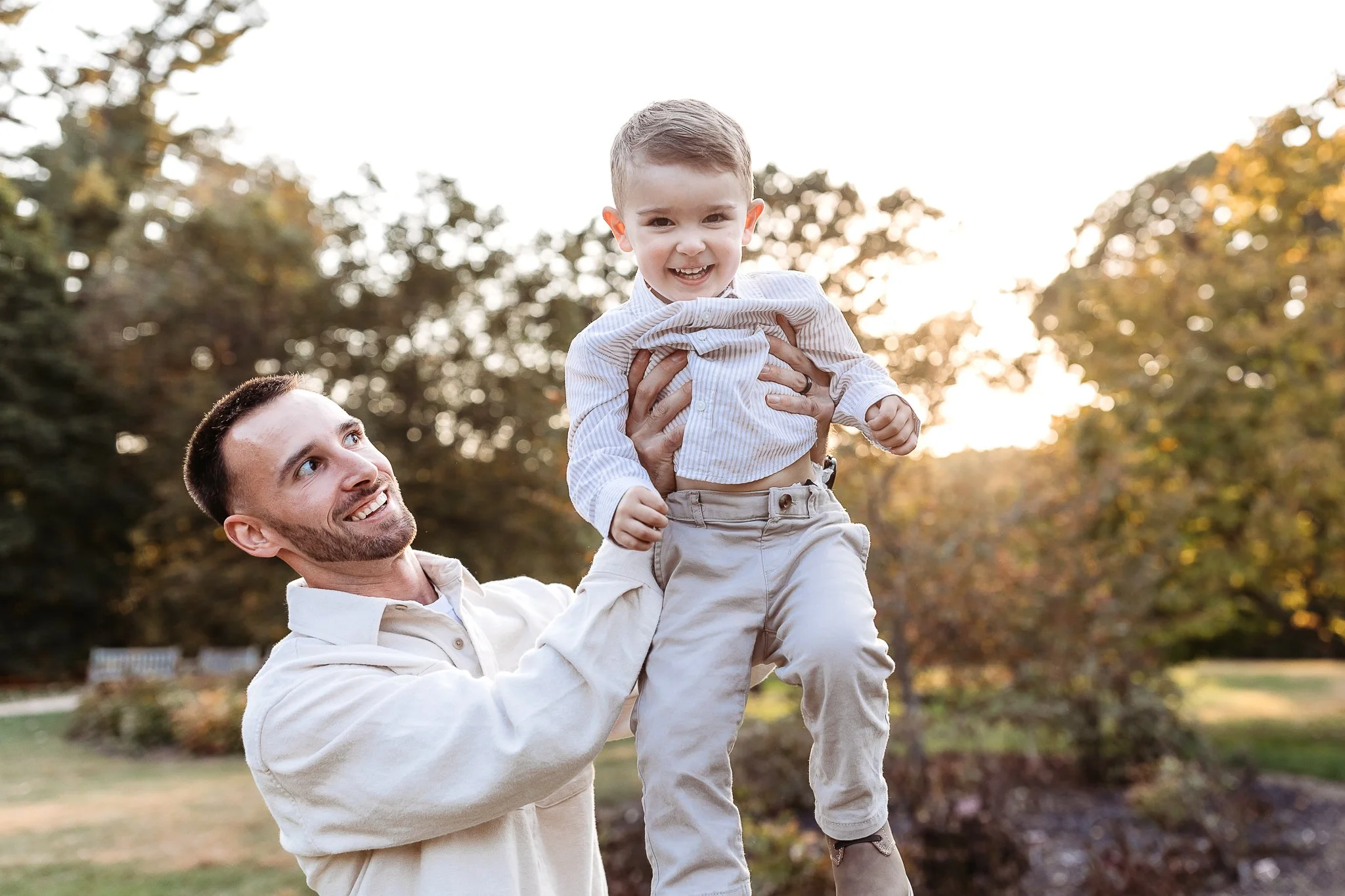 dad air planing child in the air at golden hour at a park in the Jacksonville area and they are laughing