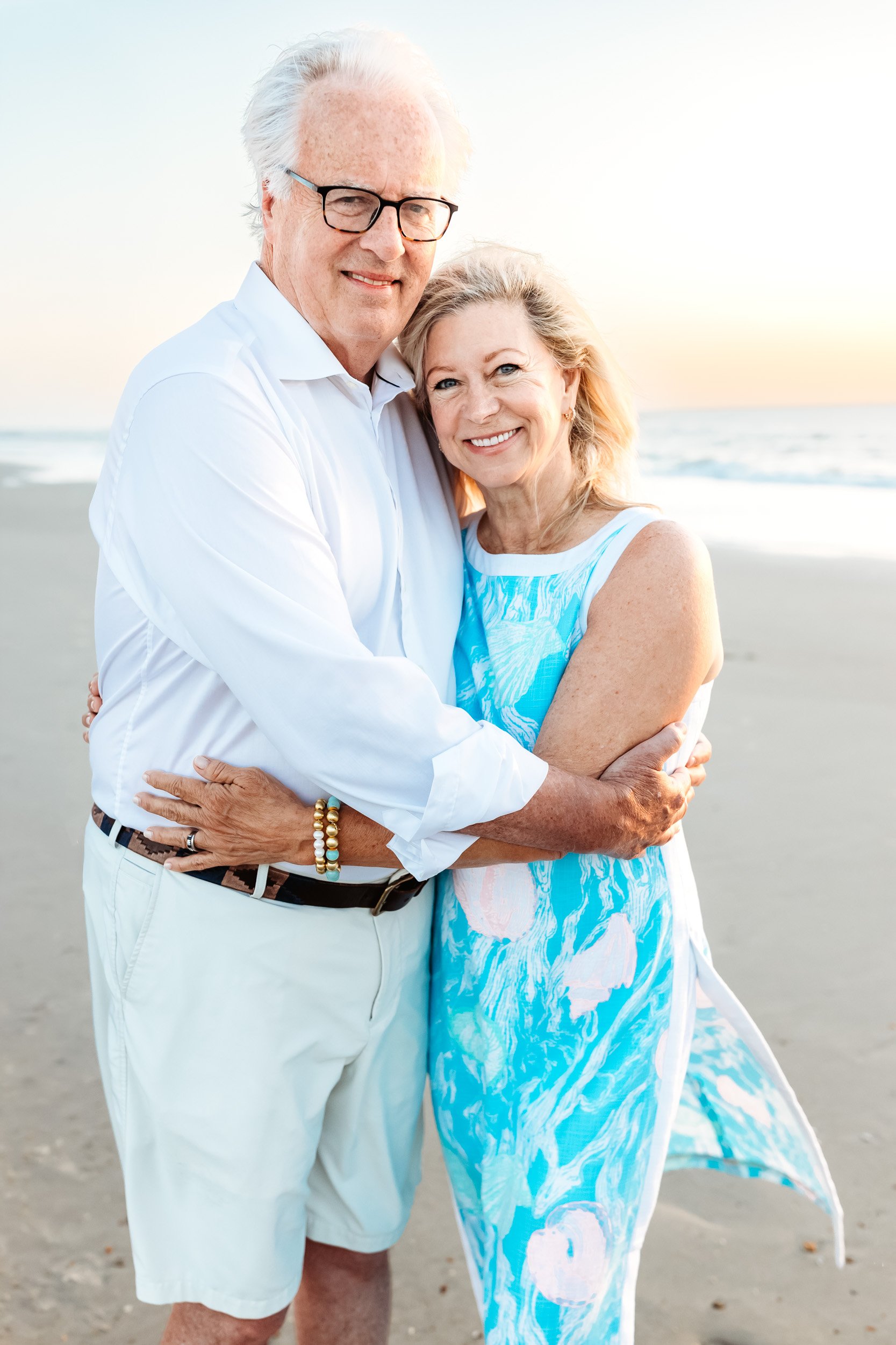 grandma and grandpa embraced for a portrait during extended family sunrise beach photos