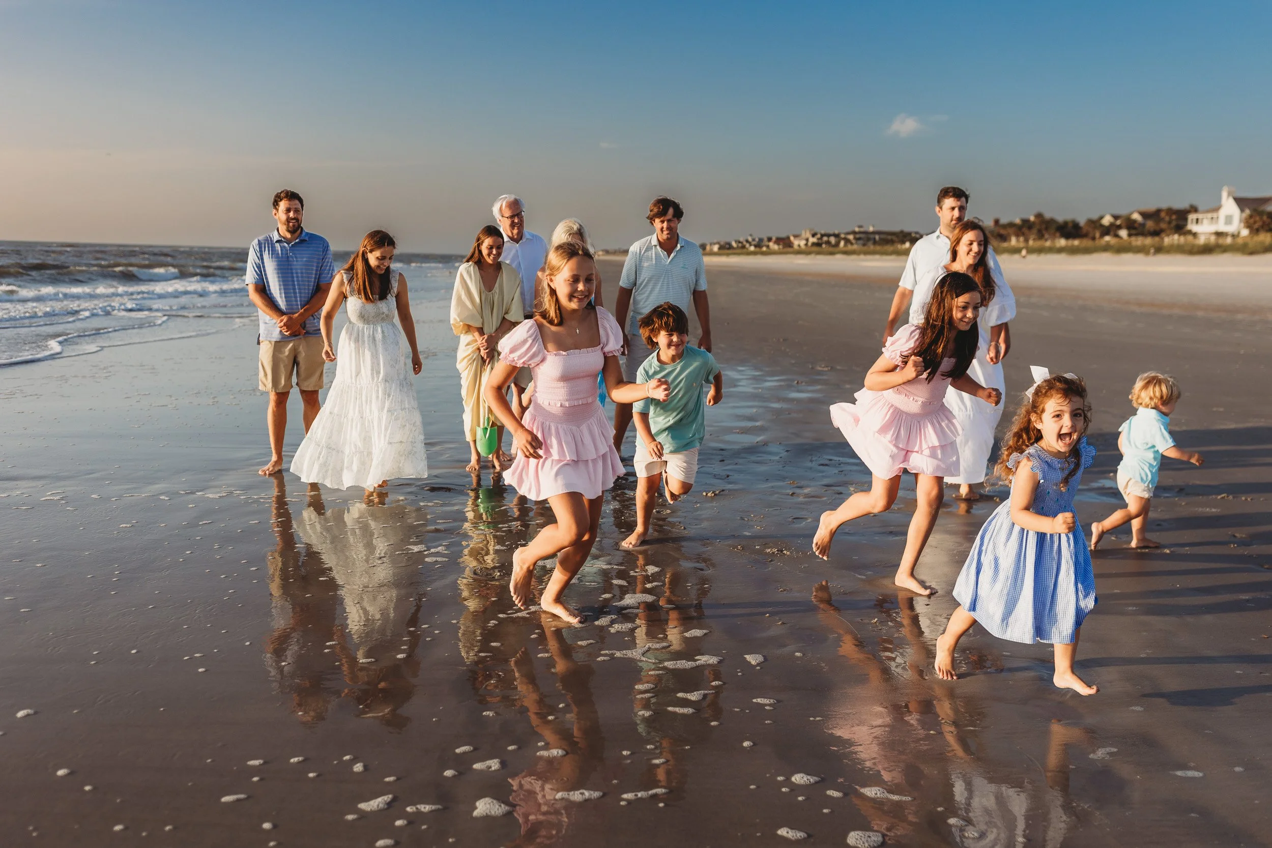 kids playing in th ocean at sunrise for family photos and they are in the waves