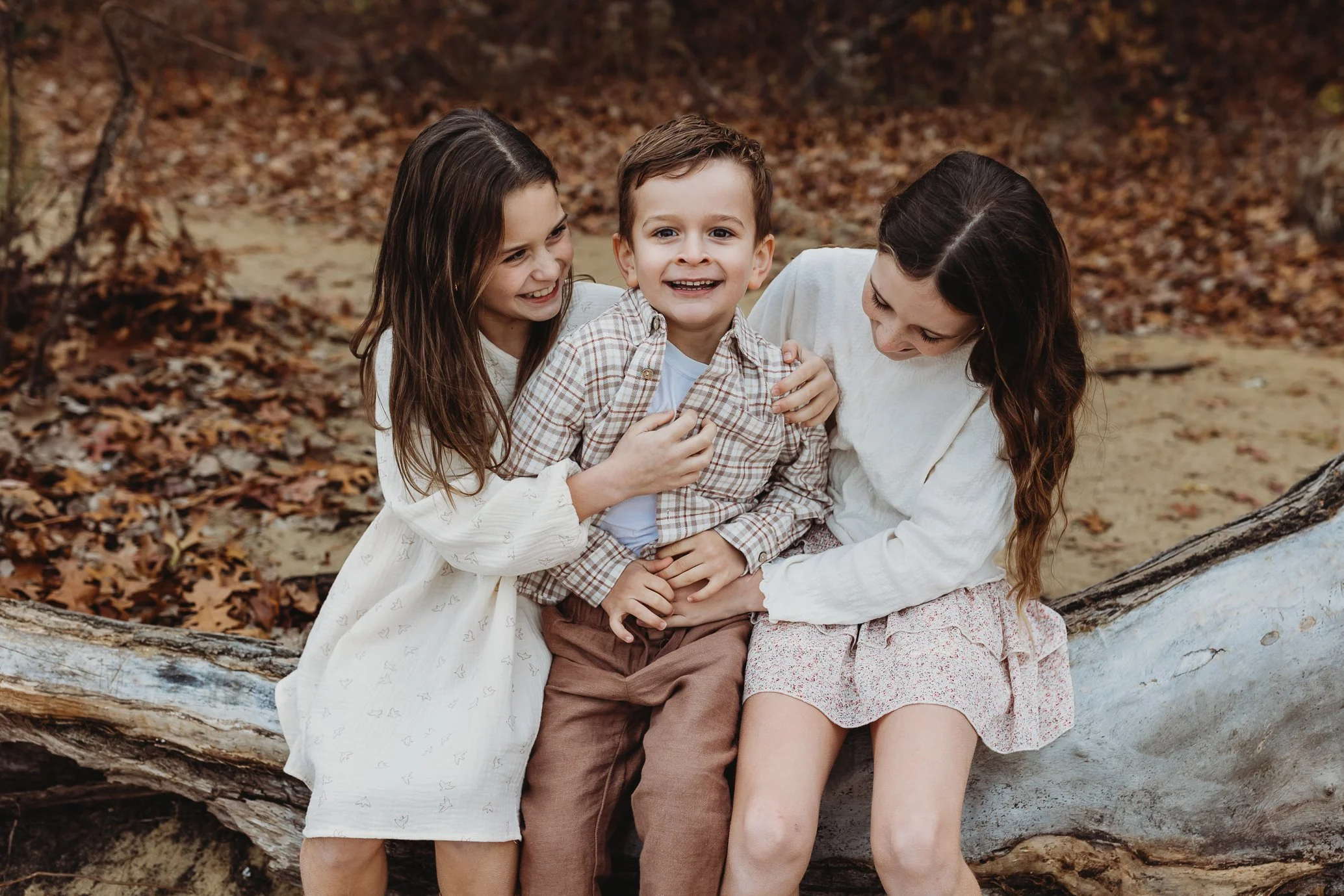 kids seated on a log laughing for pictures