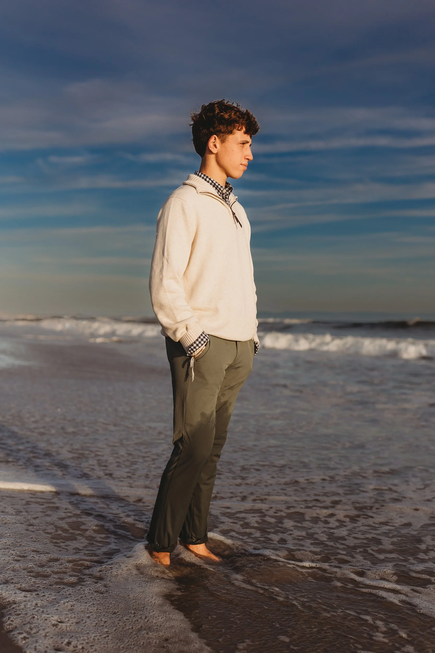 teen boy on the Villano beach at sunset staring out at ocean and hands on pocket