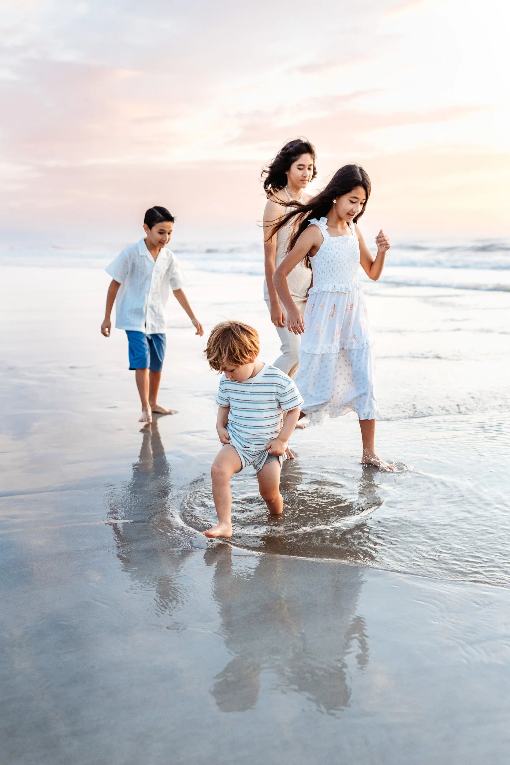 toddler boy playing in the ocean whole his cousins play
