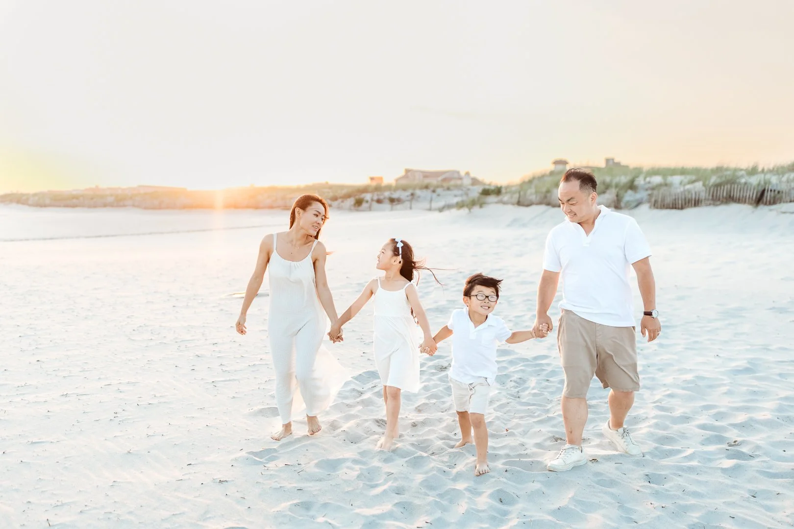Family wearing neutral outfits for beach family photos at sunset