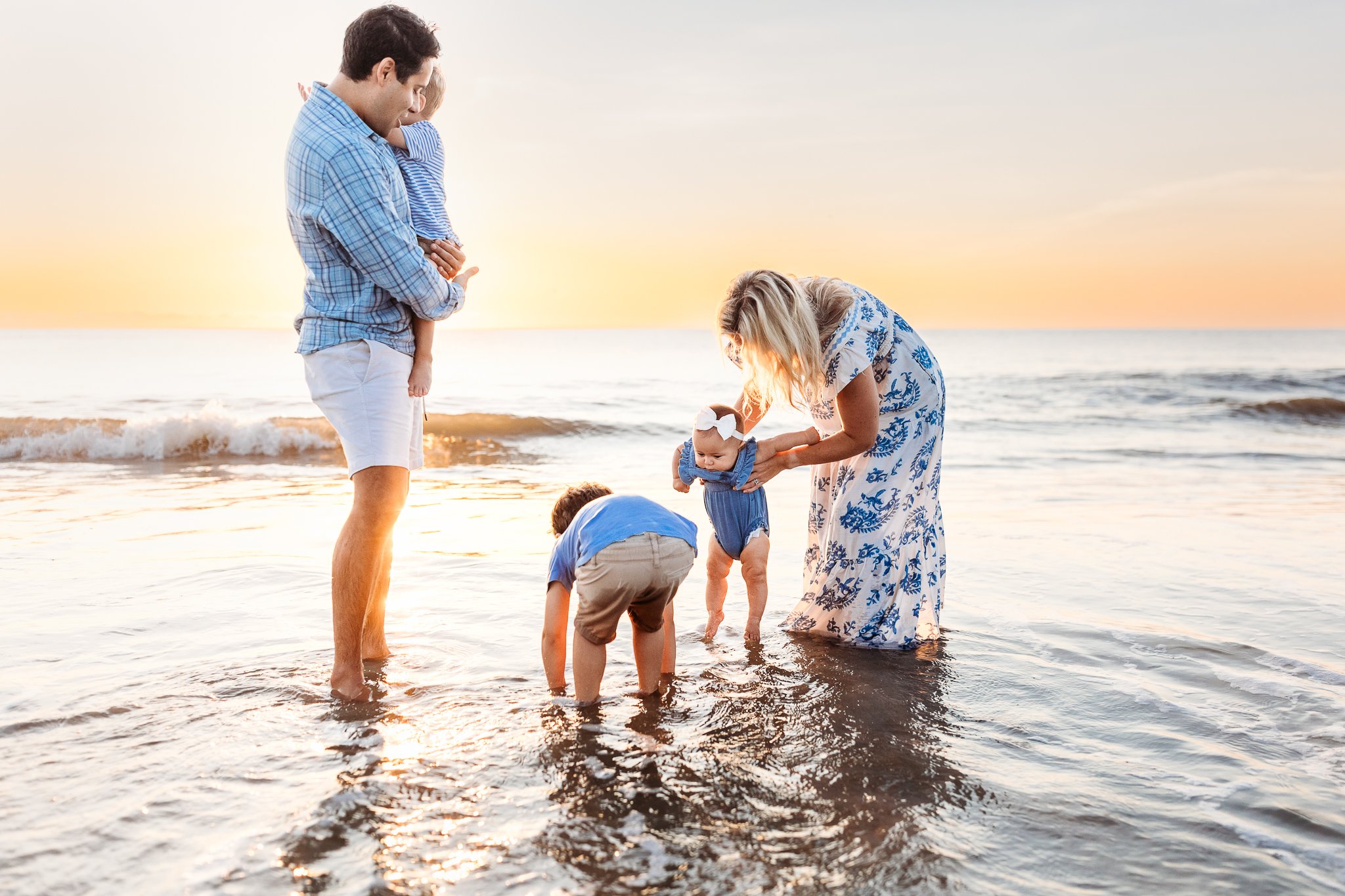 family playing in the ocean its sunrise and dipping baby's toes in the water