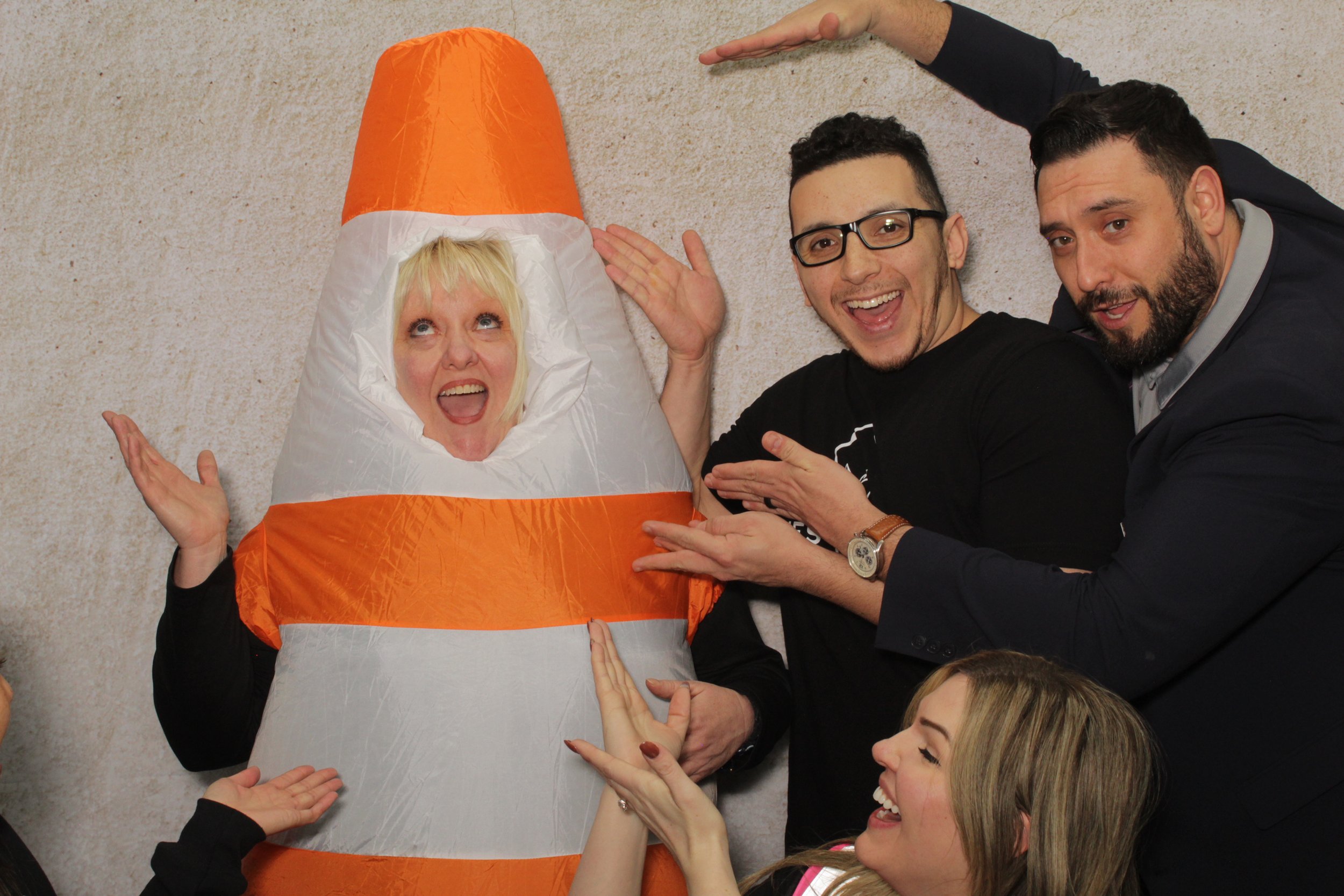 People posing with a person dressed as a traffic cone, all smiling and appearing excited.