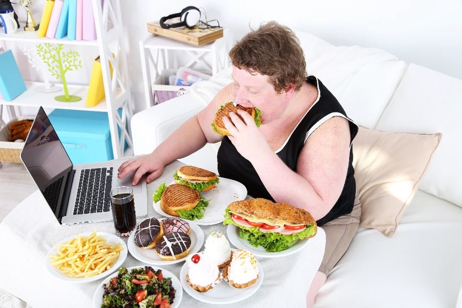How to stop binge eating at night- a woment working on a computer and eating