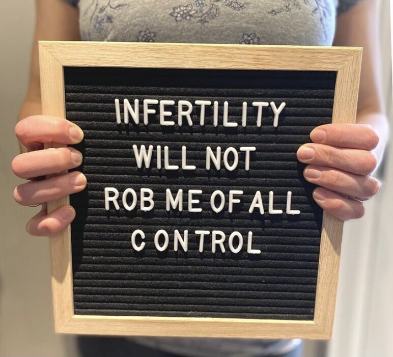 woman holding a sign that reads &quot;infertility will not rob me of all control&quot;