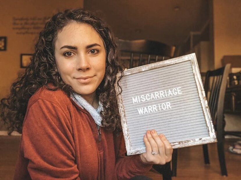 infertility warrior arden cartrette holding a sign that reads &quot;miscarriage warrior&quot;