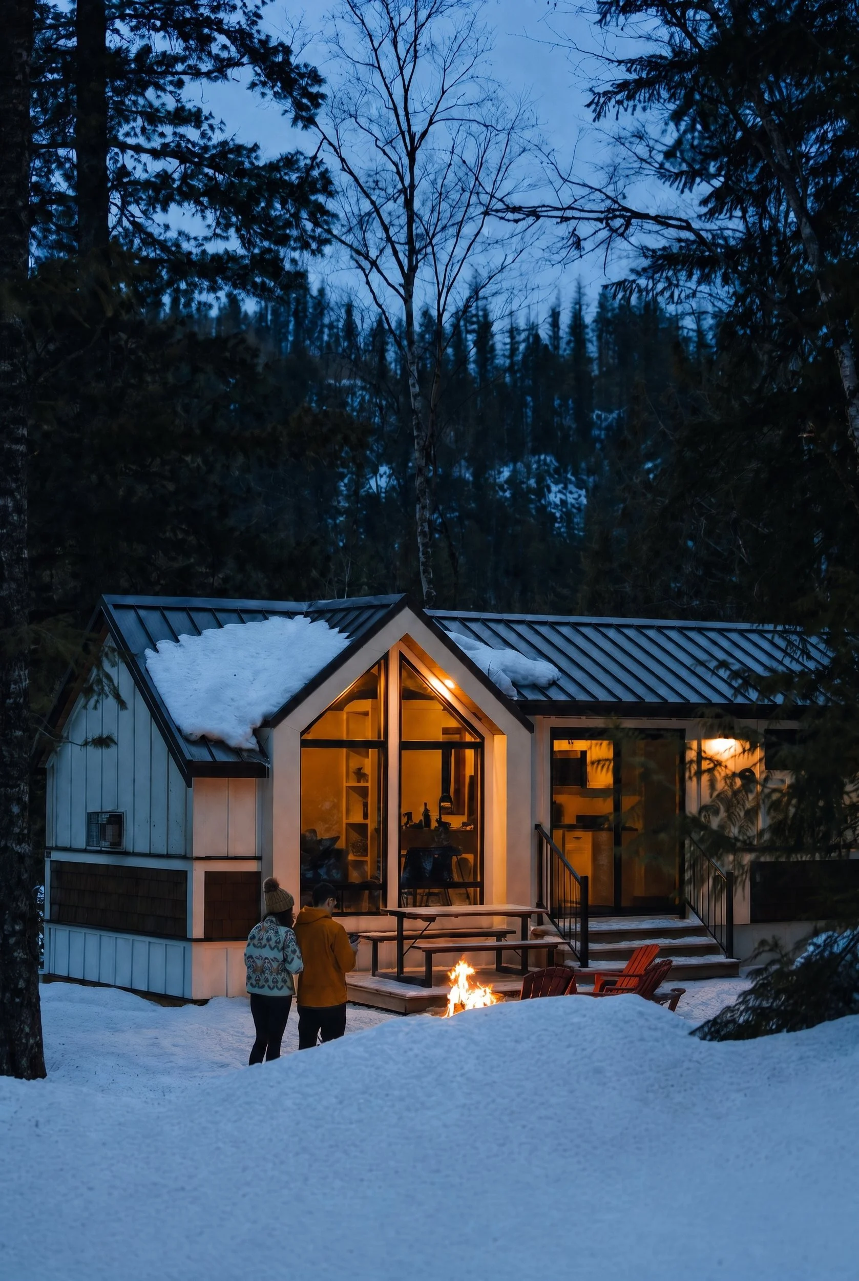The Apex in winter at dusk, with a guest by the fire pit in the snow