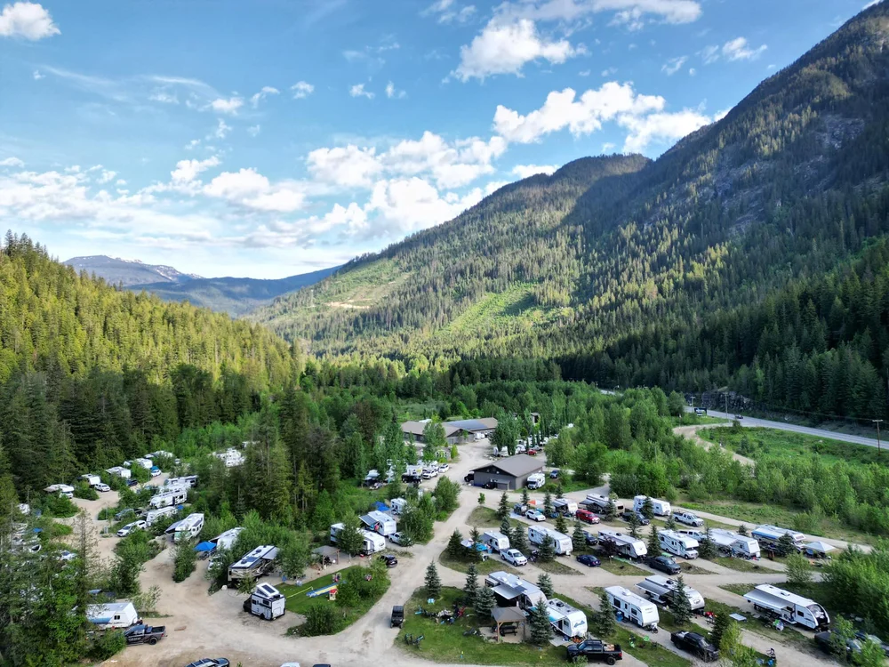 Summer view from above of the Crazy Creek campground, with RVs parked among green trees below the mountains