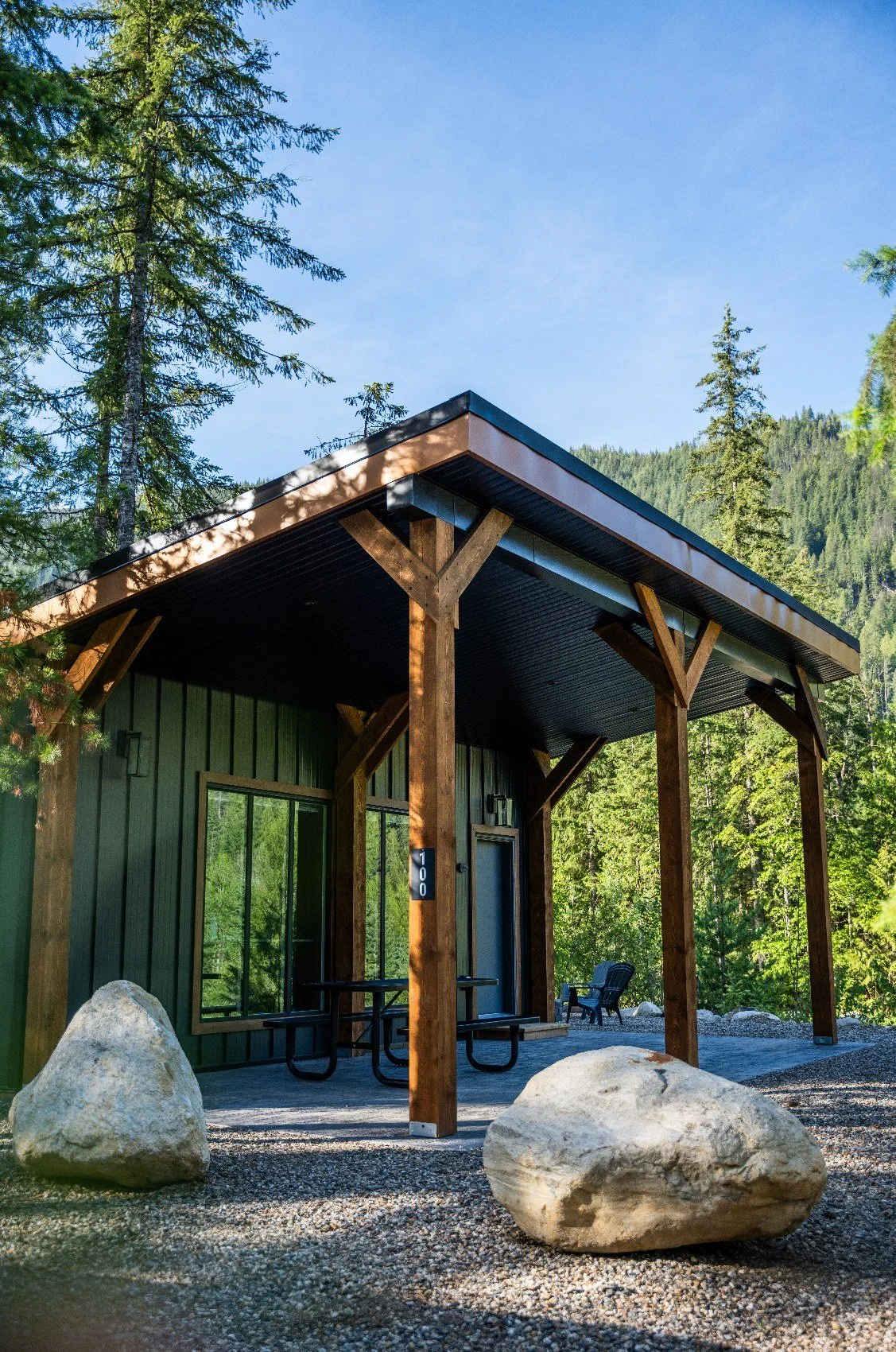 The same Monashee cabin in summer, with its covered deck and green forest behind