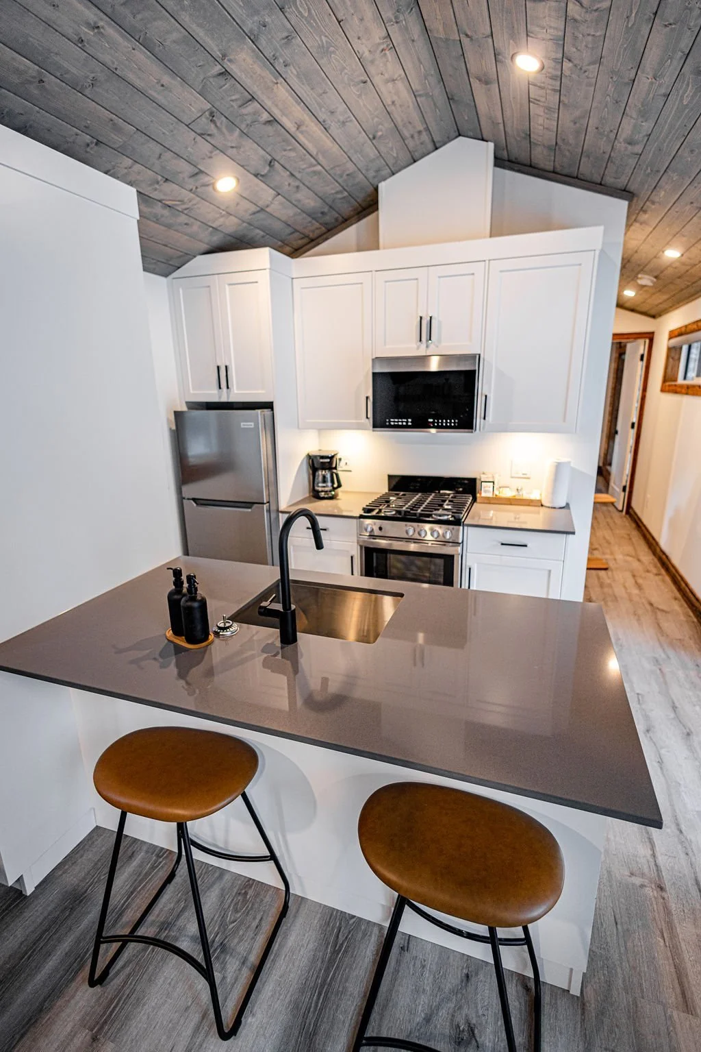 Apex kitchen with white cabinets and a breakfast bar with two stools
