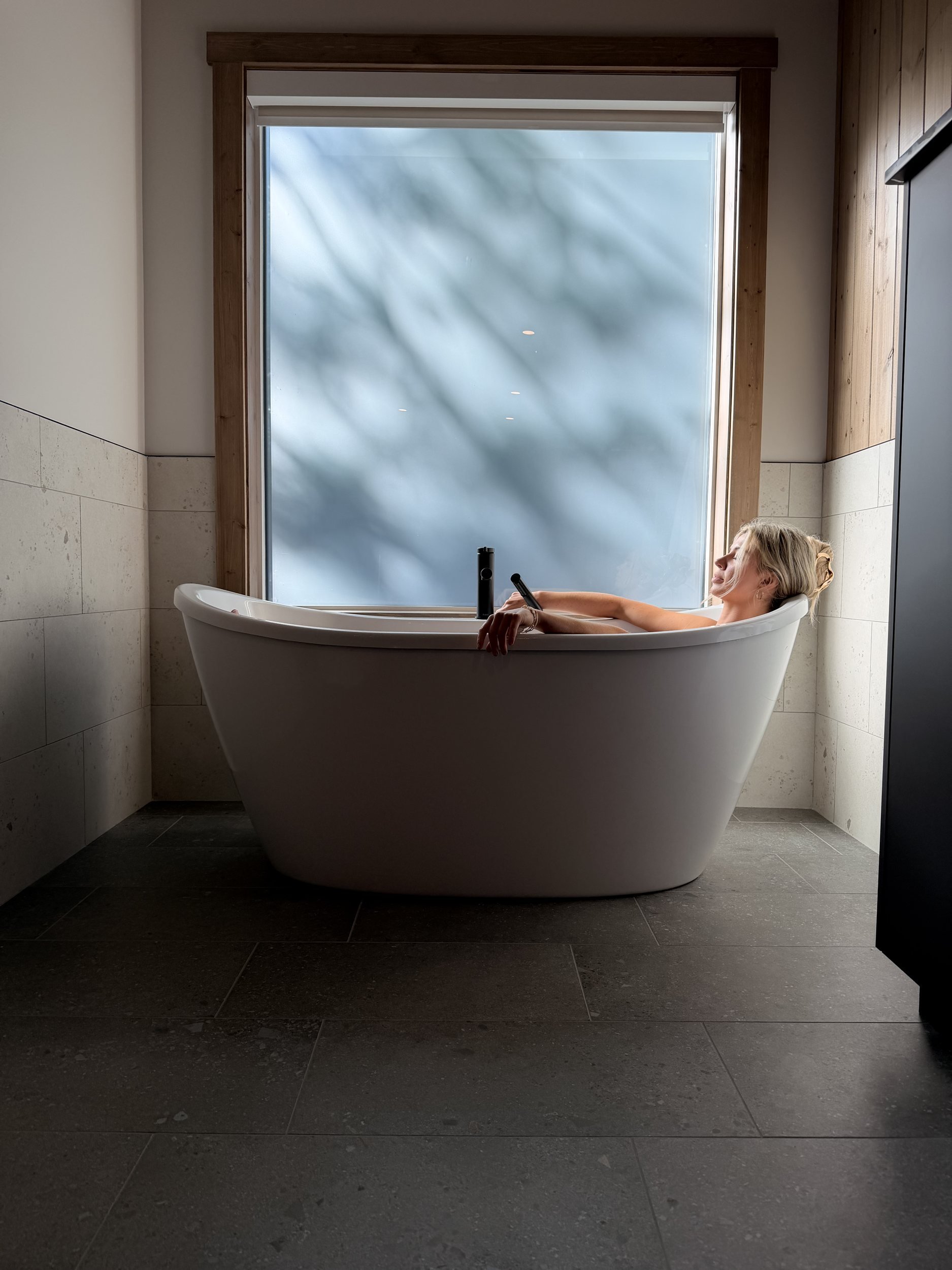 Guest relaxing in the freestanding soaker tub in the Nest