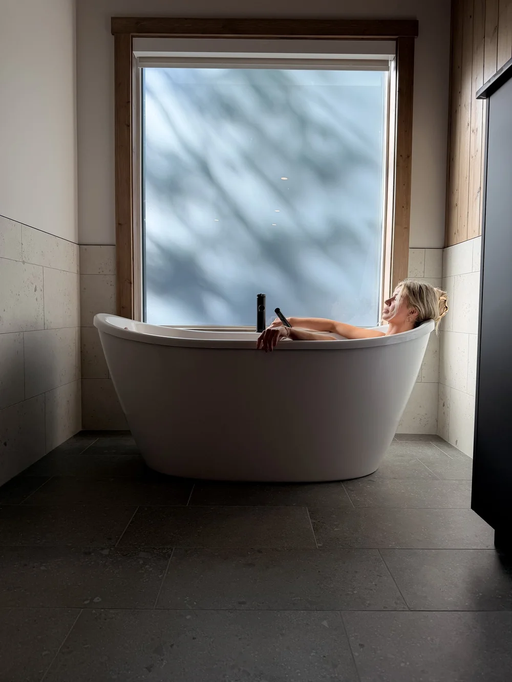 A guest relaxing in the freestanding soaker tub in the Nest