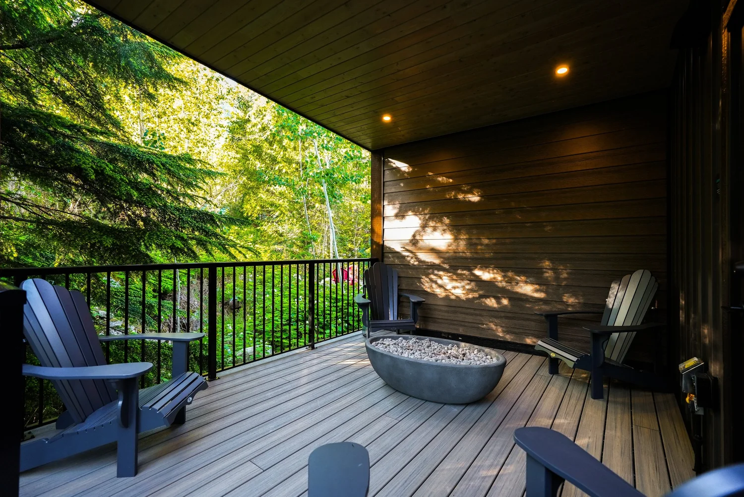 Adirondack chairs around the gas fire pit on the covered deck of the Selkirk cabin